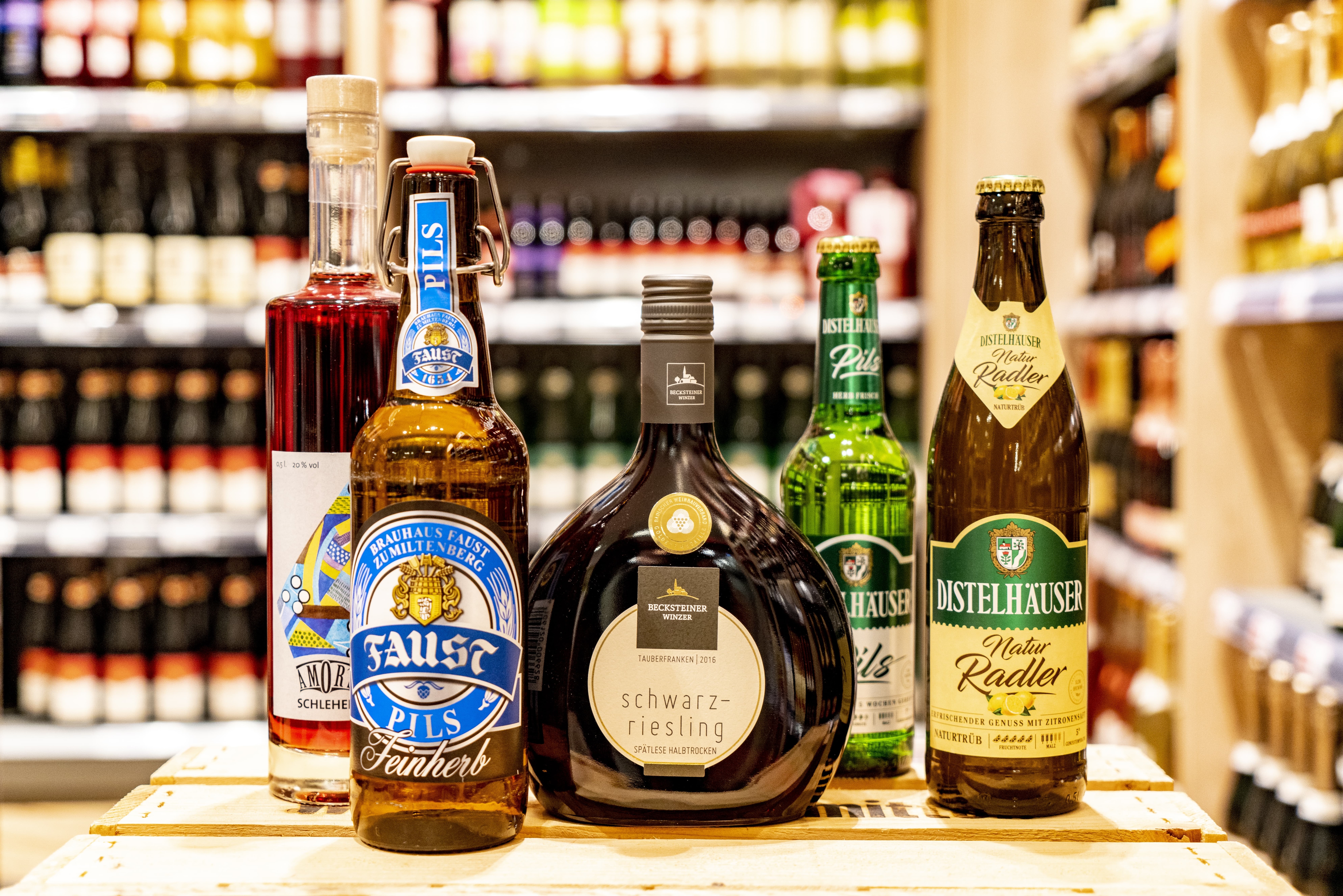 Verschiedene regionale Getränke in Glasflaschen auf einem Tisch, darunter Bier und Wein.