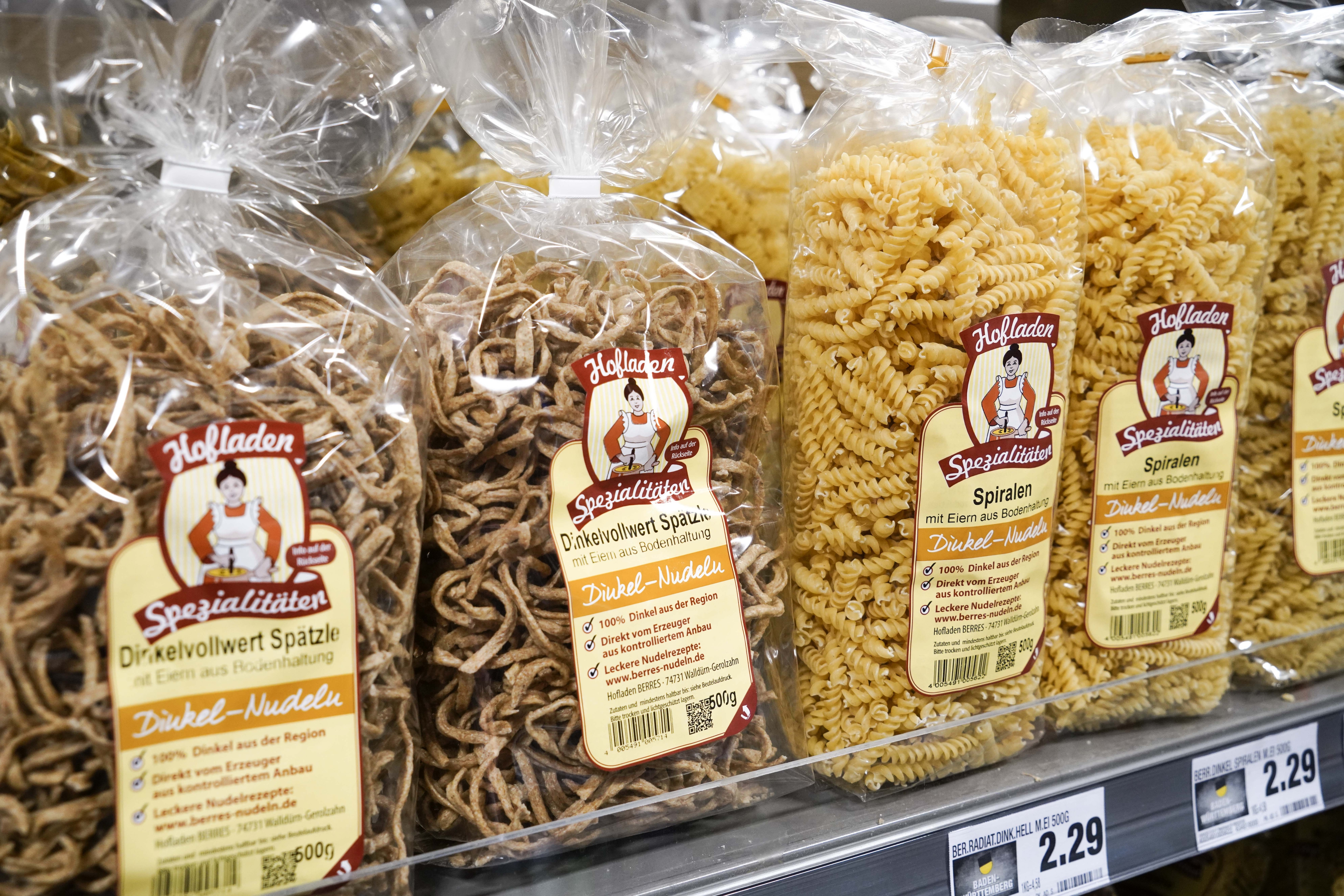 Close-Up von Nudelpackungen in einem Regal. Sie sind etikettiert mit „Hofladen-Spezialitäten“.