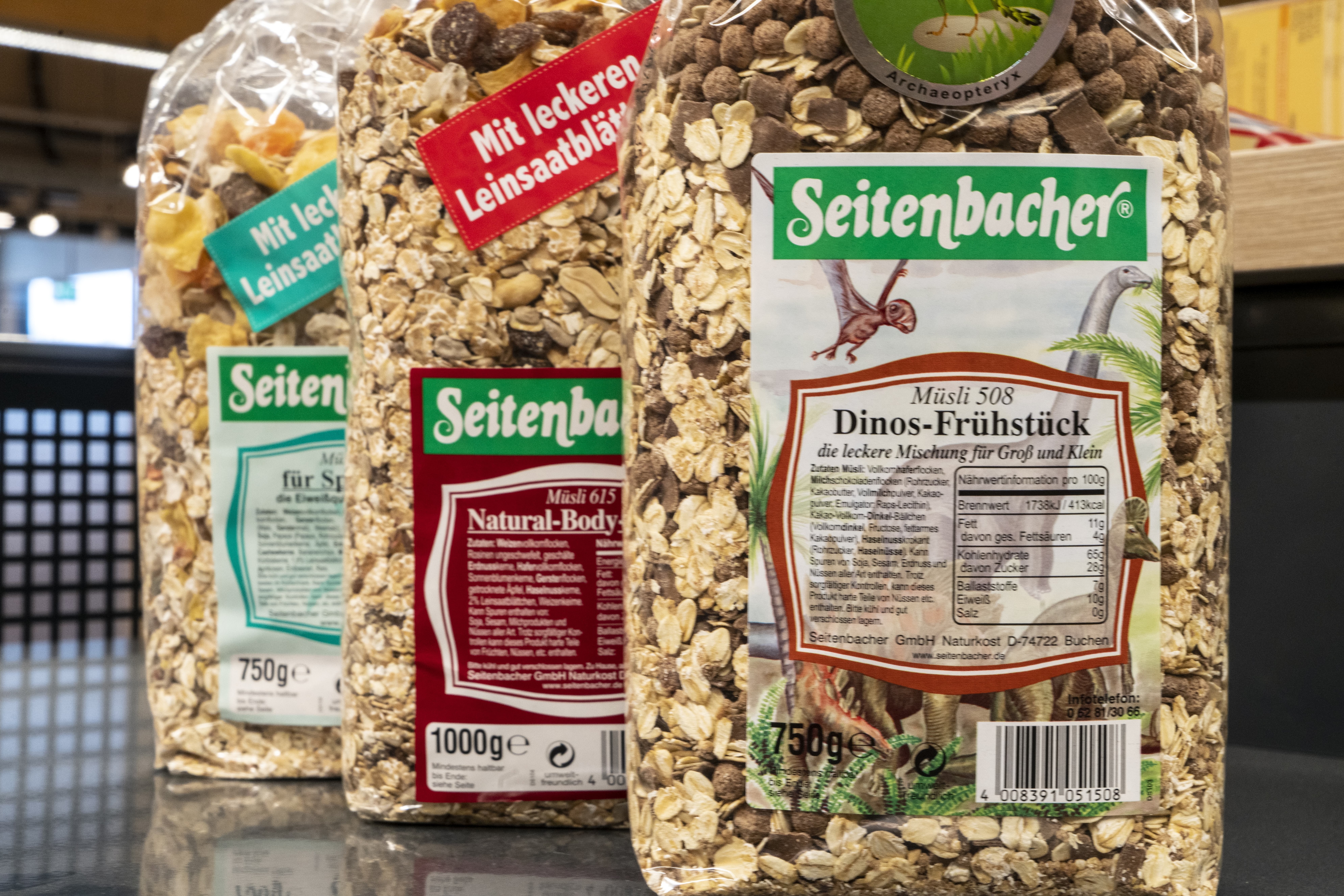 Close-Up einiger Packungen Seitenbacher-Müsli in verschiedenen Sorten, im Vordergrund die Sorte Dino-Frühstück.