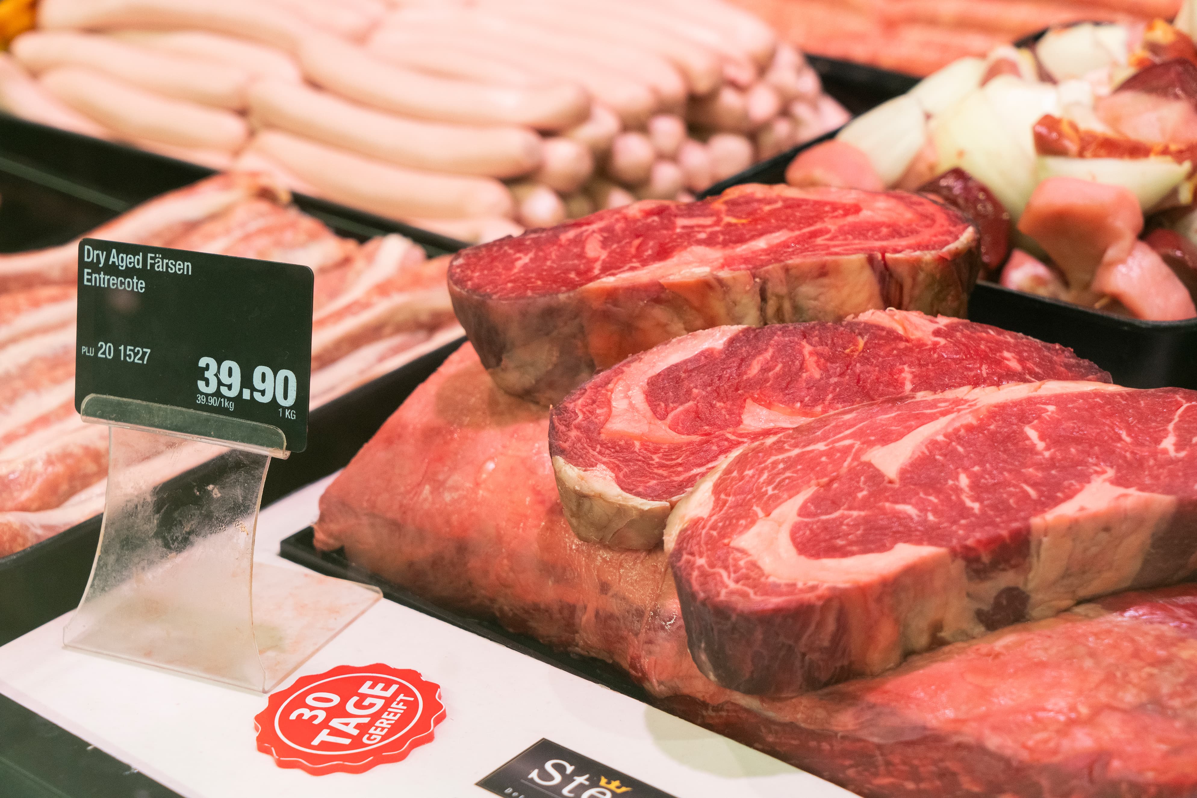 Close-Up einer Fleischauslage mit Preisschildern.