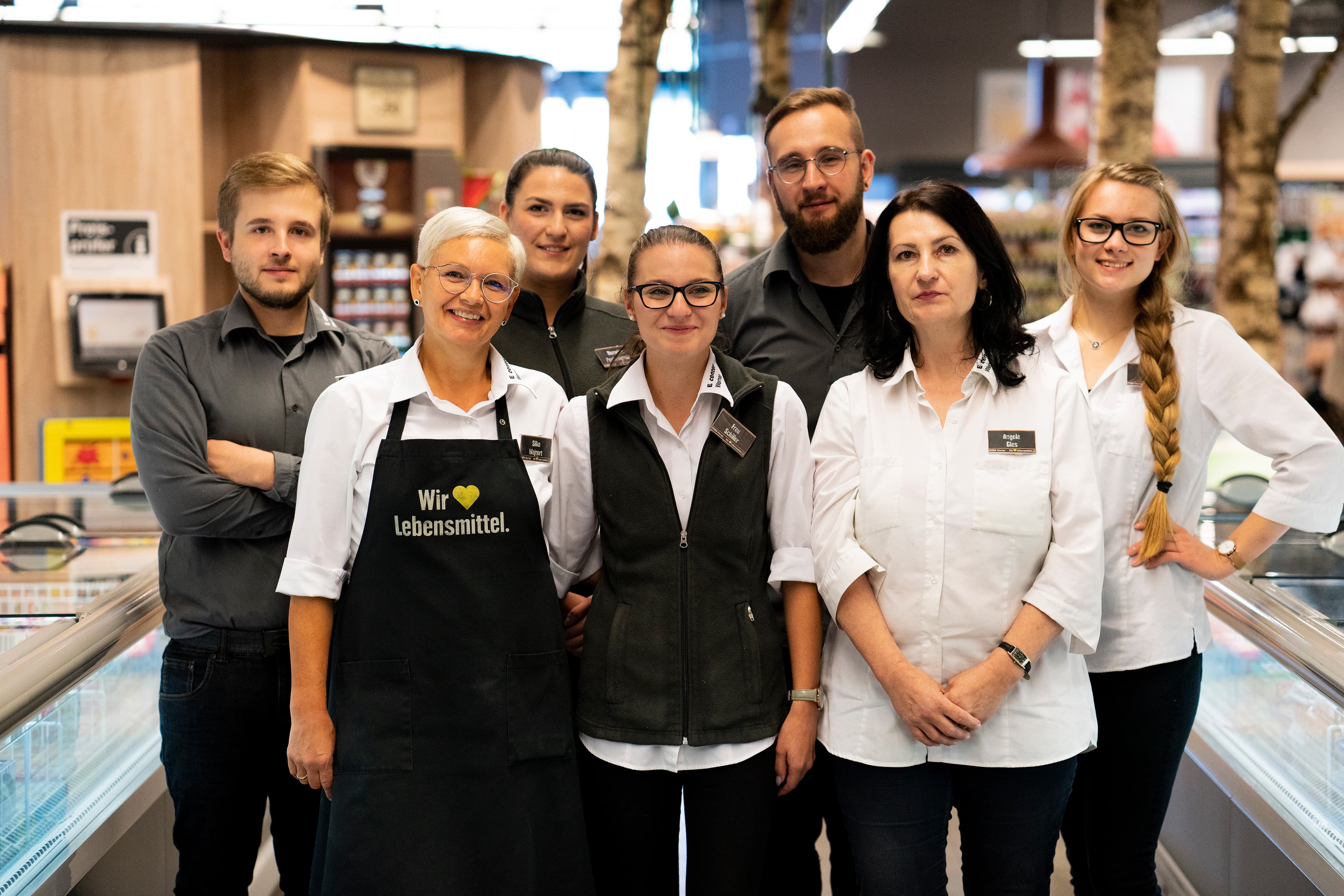 Gruppenfoto des Teams dieses EDEKA-Markts, aufgenommen im Gang im Tiefkühlbereich.