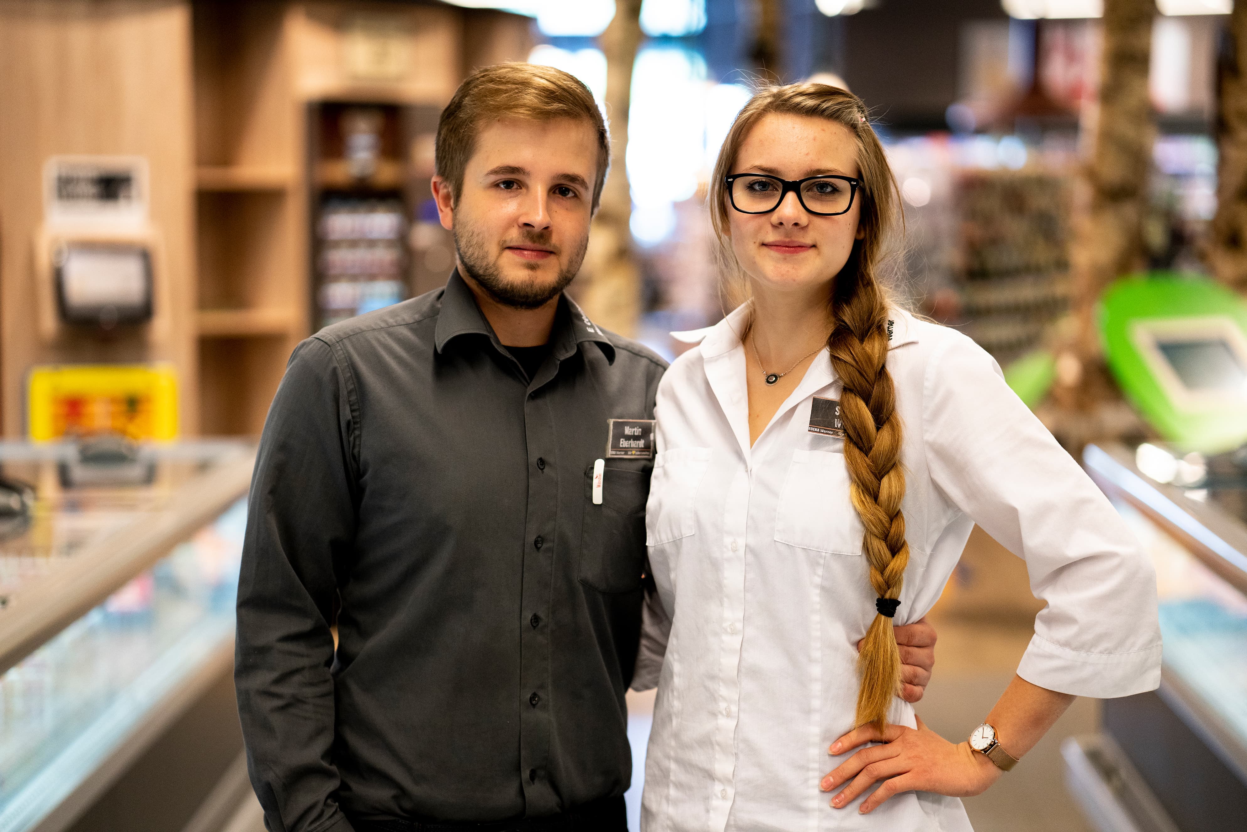 Ein Mitarbeiter und eine Mitarbeiterin stehen Arm in Arm in der Tiefkühlabteilung eines EDEKA-Markts.