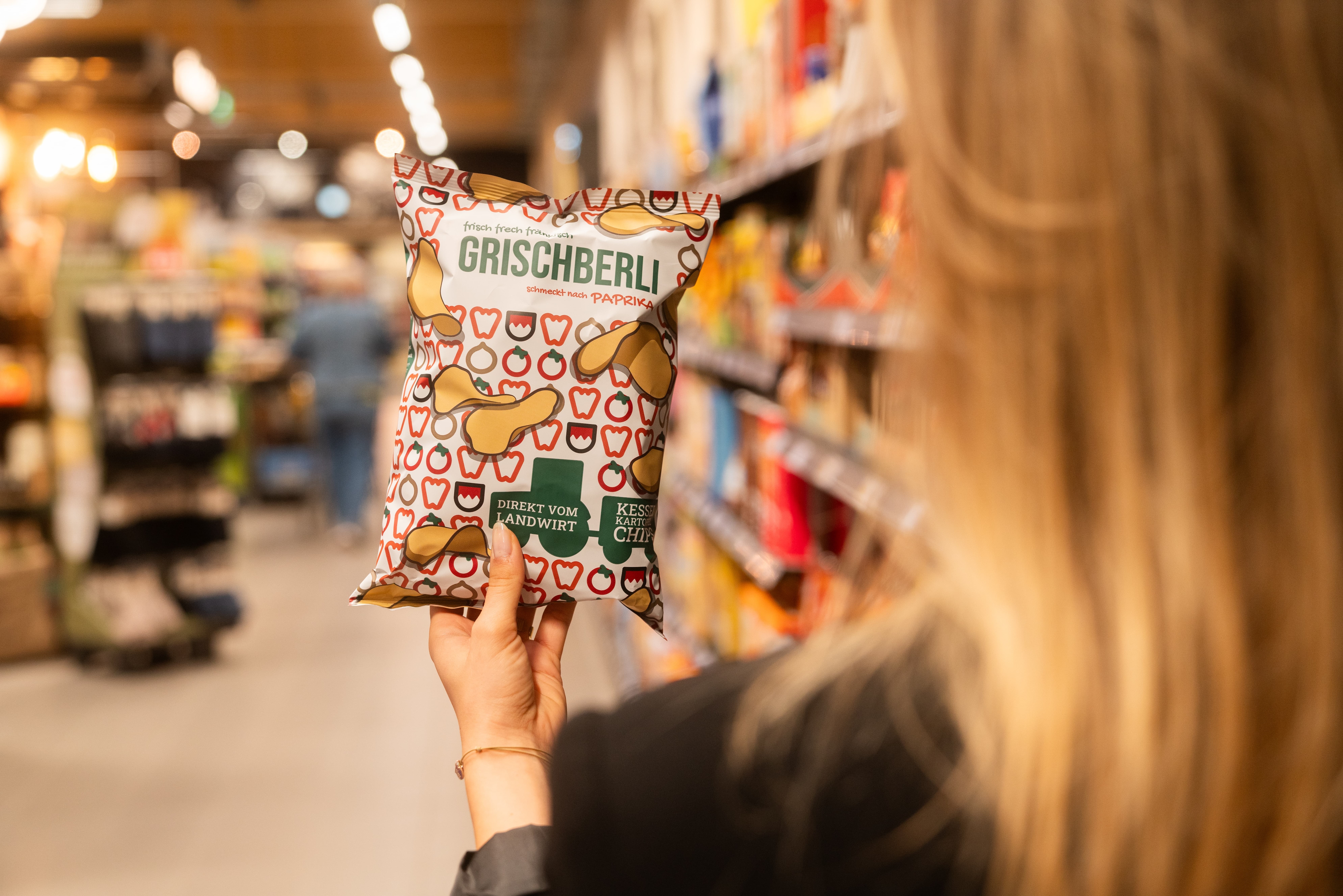 Eine Frau hält eine Tüte Chips der Marke Grischberli in der Hand.