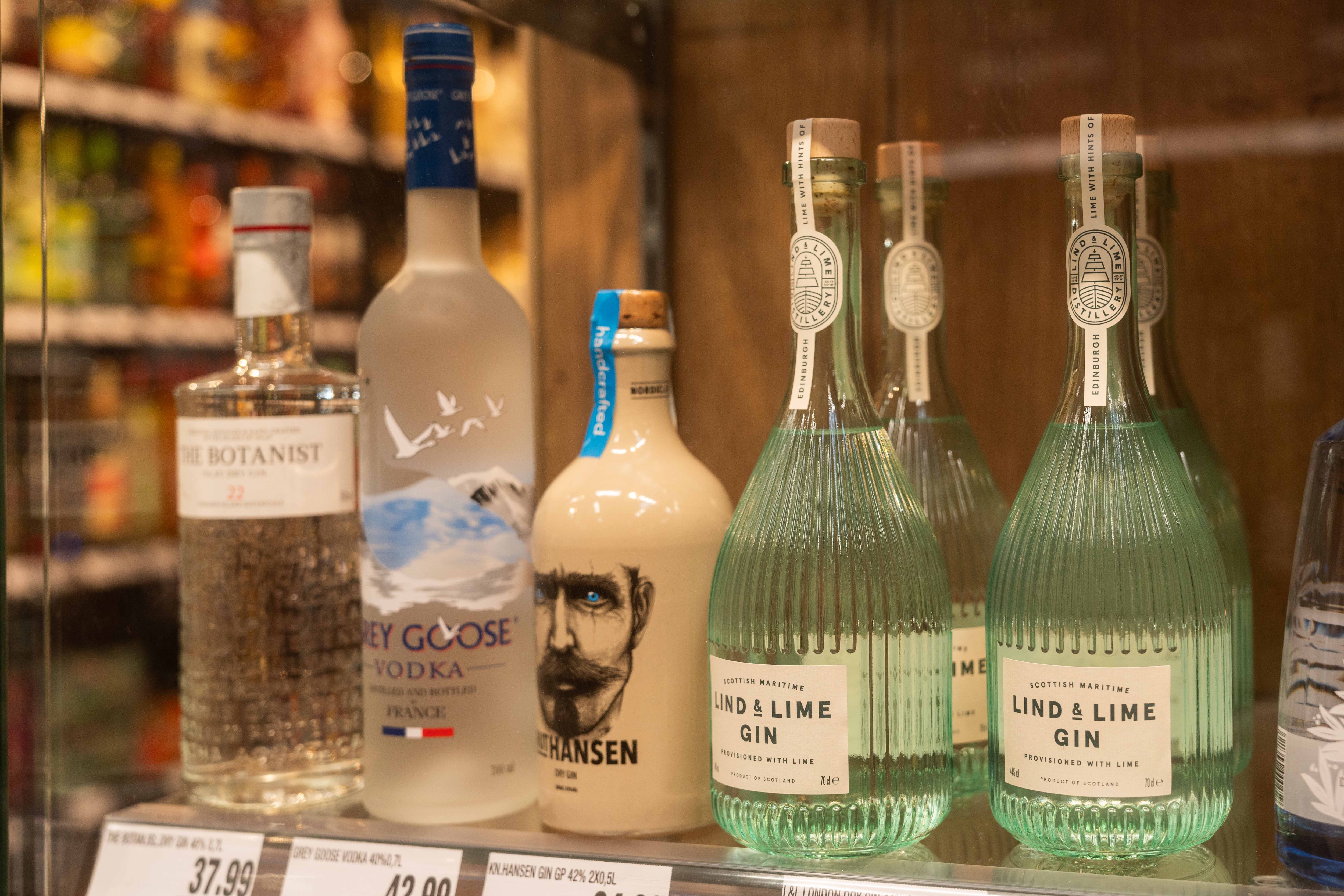 Verschiedene Ginsorten sind auf einem Regalfach in der Glasvitrine zu sehen.