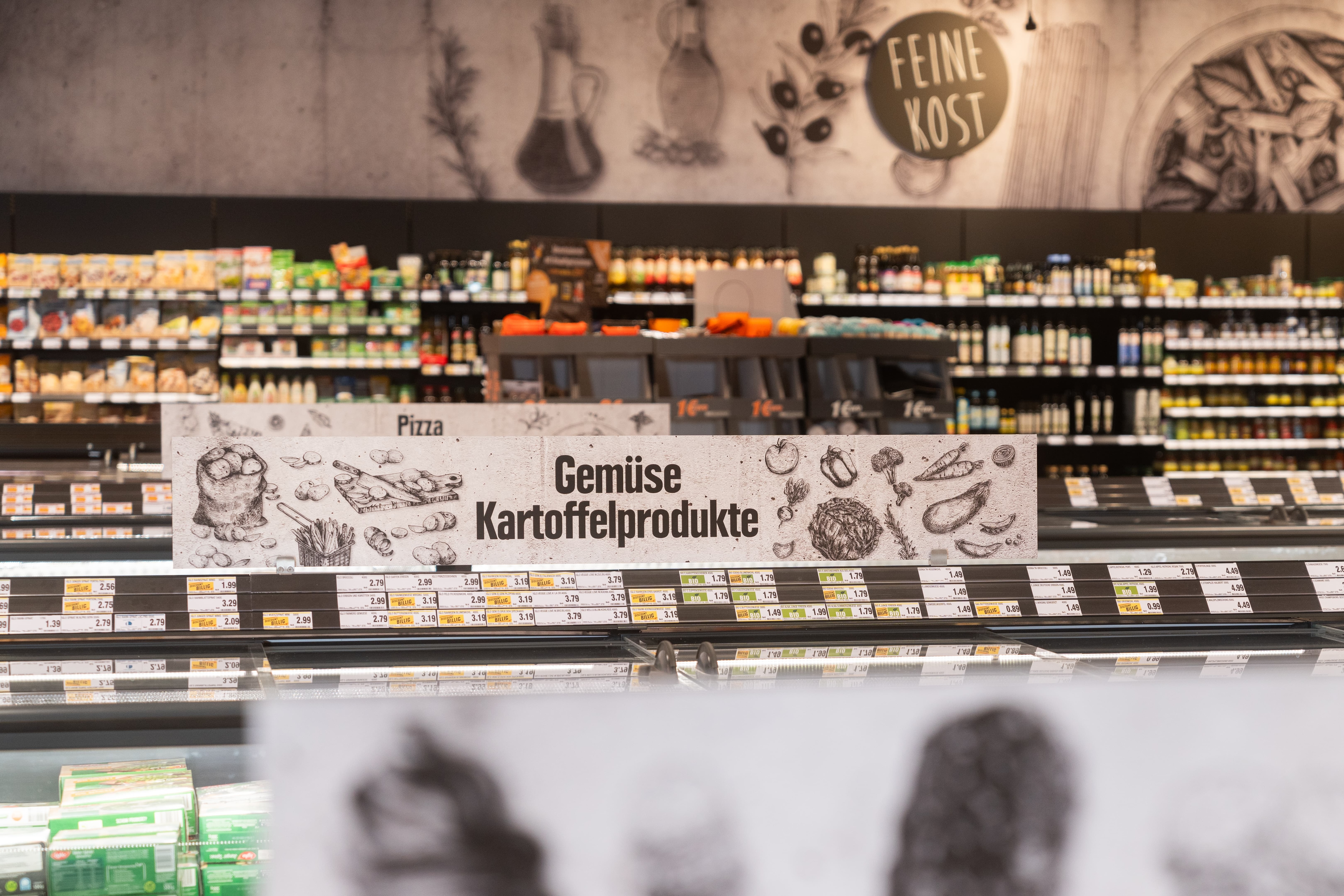 Über einer Tiefkühltruhe steht Gemüse Kartoffelprodukte.