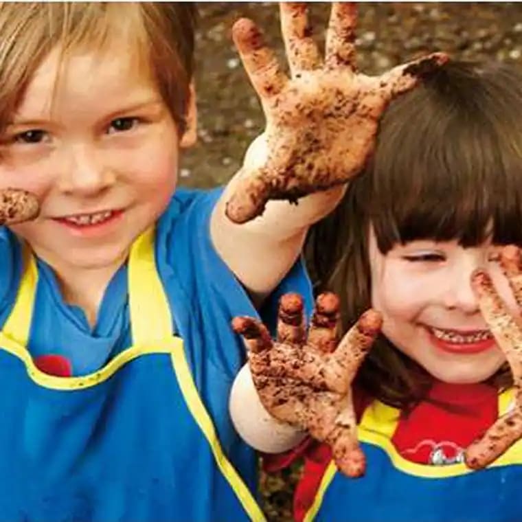 Zwei lächelnde Kinder zeigen ihre schmutzigen Hände.