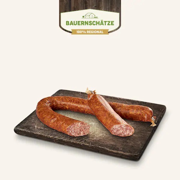 Eine lange sächsische Bratwurst auf einem dunklen Holzbrett.