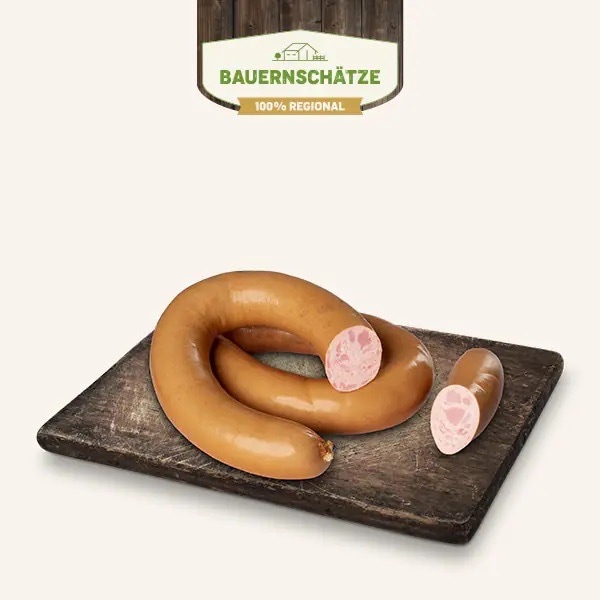 Eine lange Schinkenfleischwurst auf einem dunklen Holzbrett.