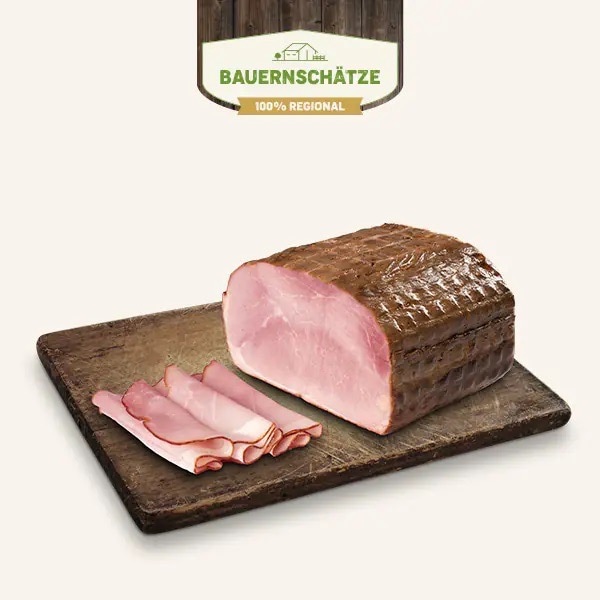 Ein Stück Wacholderschinken sowie drei dünn geschnittene zusammengerollte Scheiben.