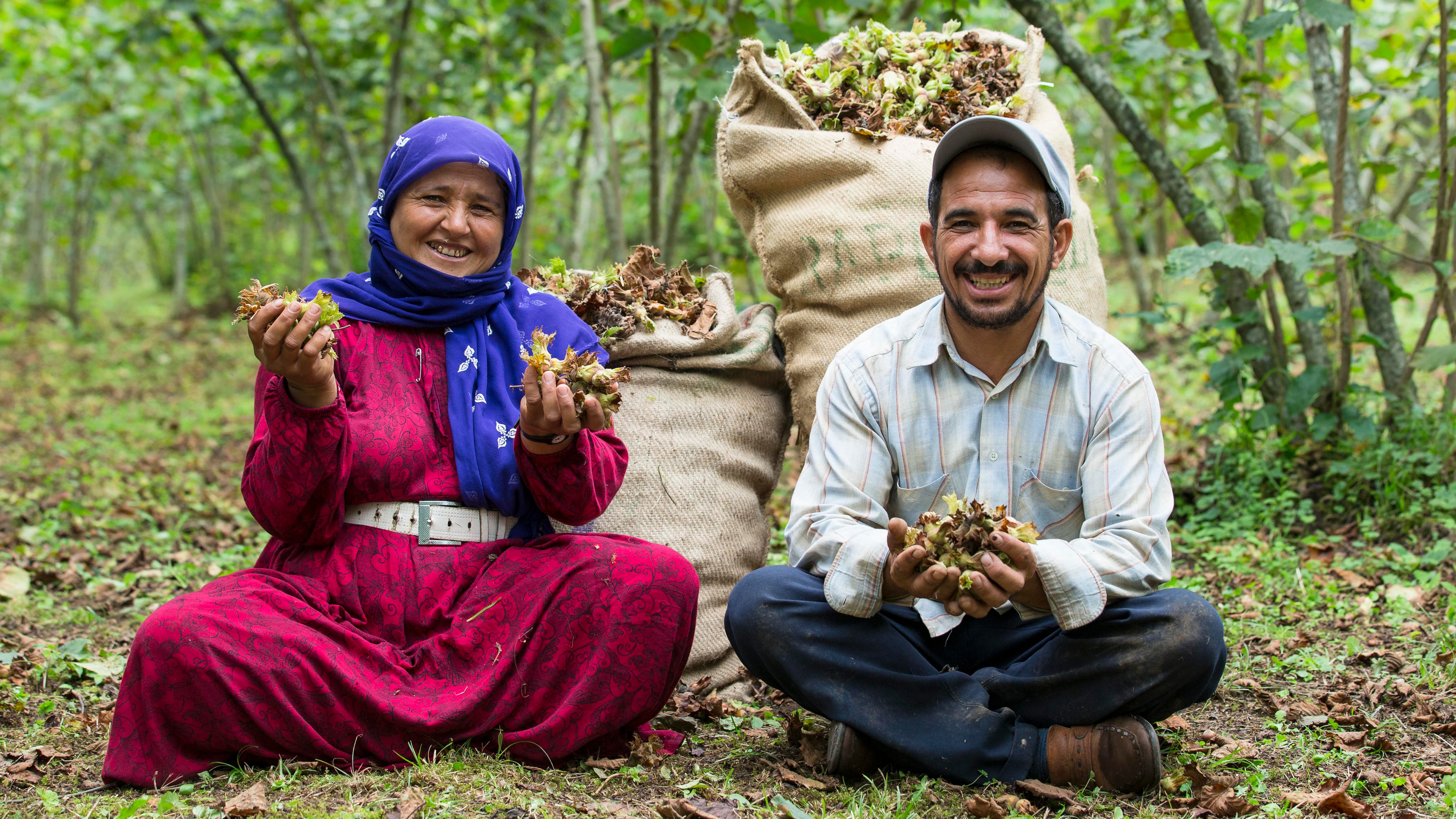 Eine Frau und ein Mann sitzen auf dem Boden und halten die Rohstoffe ihres Produkts in den Händen