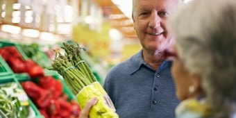 Ein älterer Herr hält einen Bund grünen Spargel in der Hand.