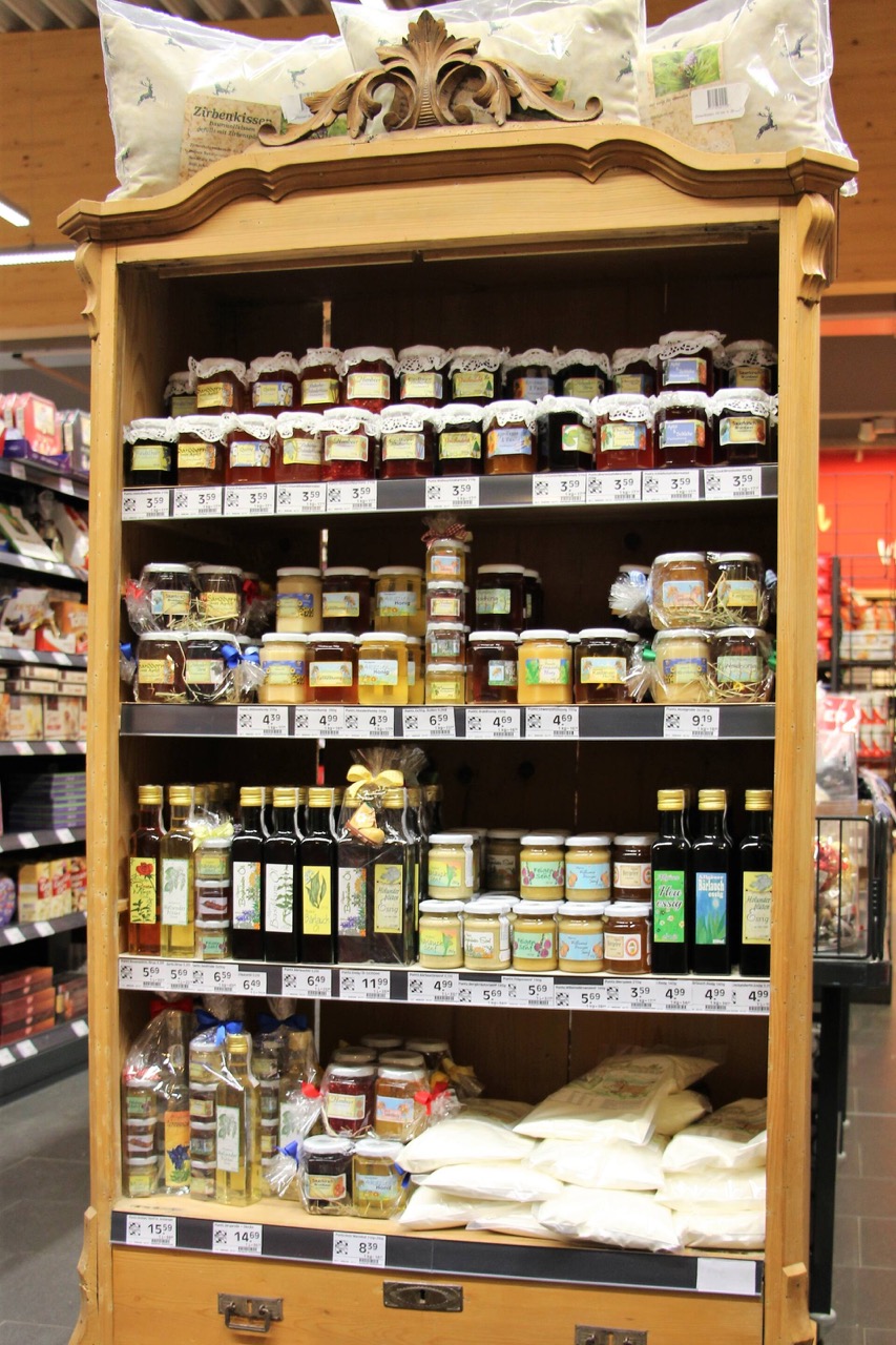 Offene Holzvitrine mit Marmeladengläsern sowie Essig und Öl.