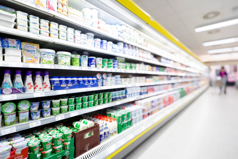 Gang mit offenen Kühlregalen für Molkereiprodukte.