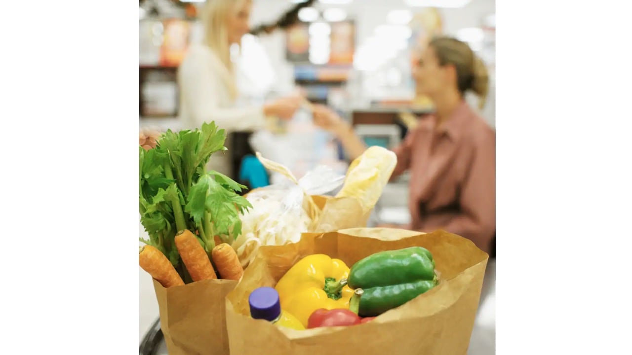 Zwei Papiertüten mit Lebensmitteln wie Möhren, Paprika und Wasser.