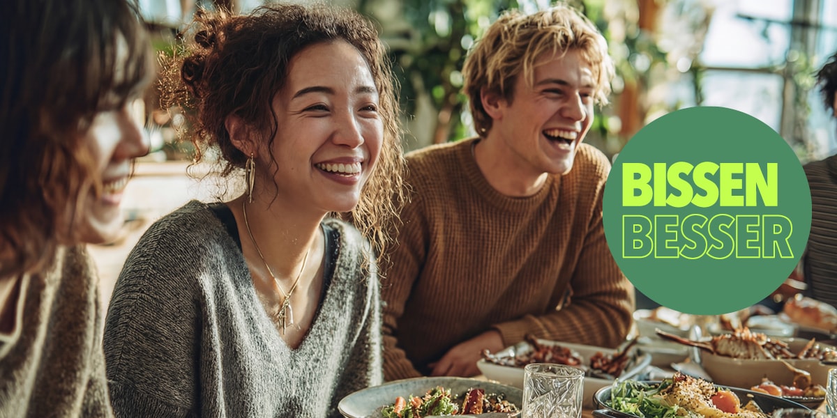 Freunde lachen beim gemeinsamen Essen; rechts grüner Kreis mit „BISSEN BESSER“.