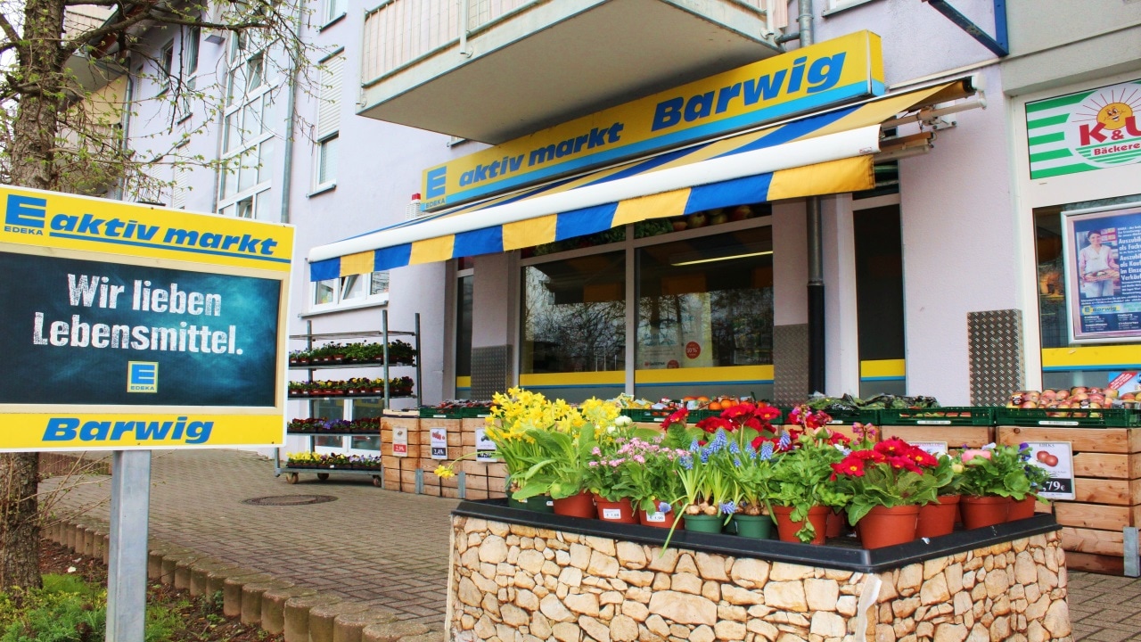EDEKA aktiv markt Barwig mit Blumenverkauf vor dem Eingang und dem Slogan „Wir lieben Lebensmittel.“