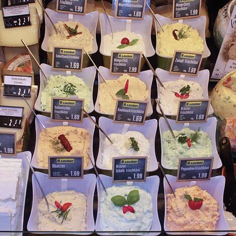 Eine Auswahl von verschiedenen Frischkäsesorten in der Auslage einer Theke.
