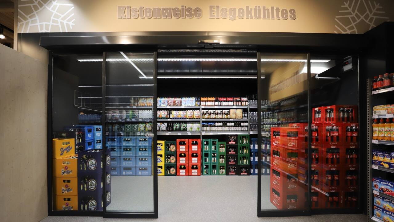 Eingangsbereich zum Kühlraum für Getränkekisten. Über der Glasschiebetür steht Kistenweise Eisgekühltes.