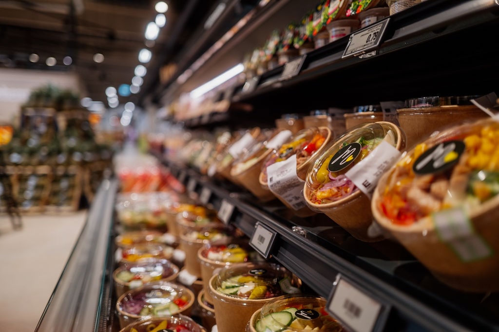 Frische Salatbowls und To-go-Gerichte im Kühlregal eines Supermarkts.