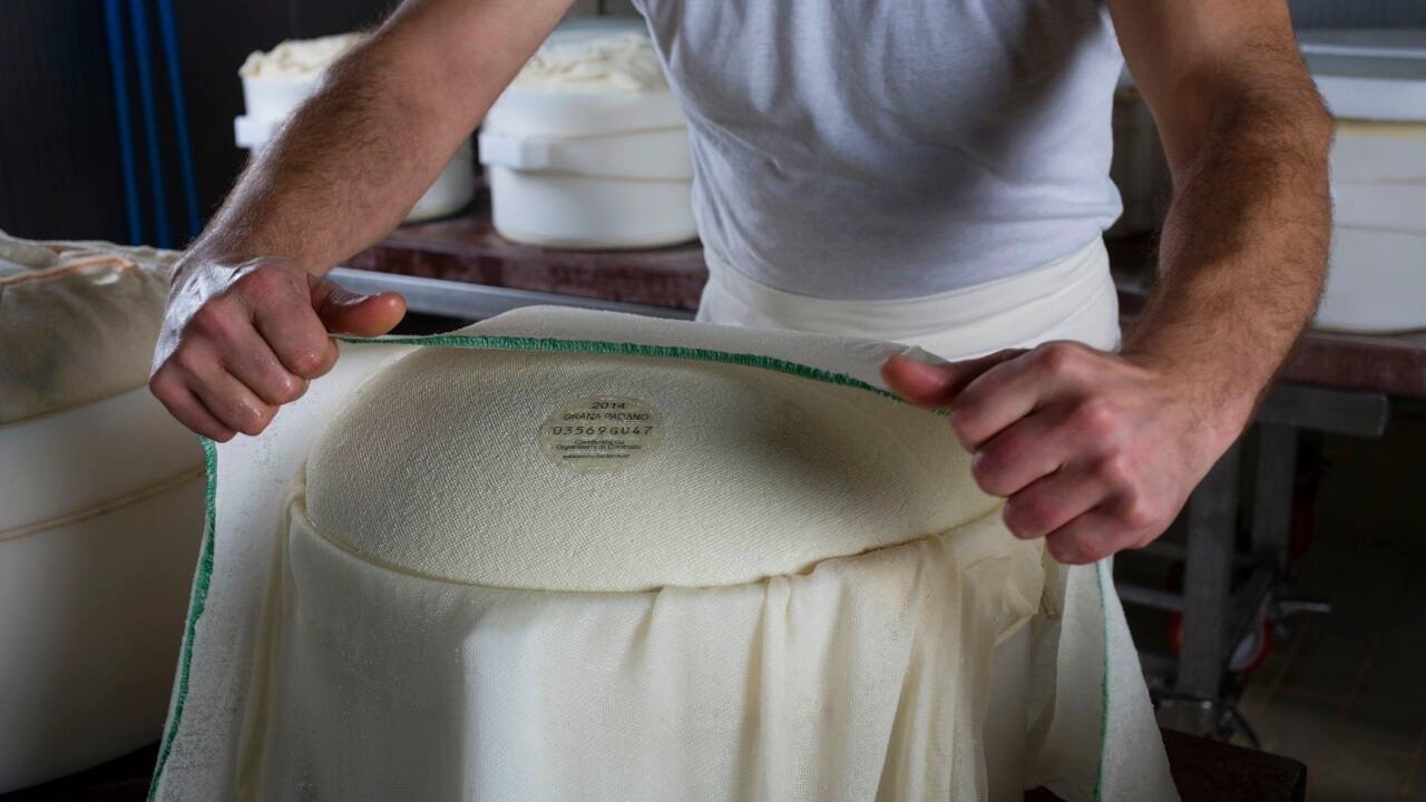 Ein Mann spannt ein weißes Stück Stoff über eine weiße Masse.