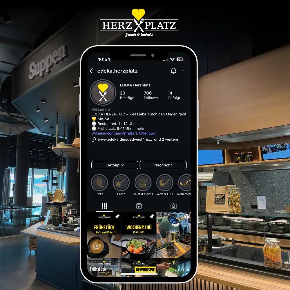 Smartphone mit der Instagram-Seite des Restaurant Herzplatz auf dem Screen. Im Hintergrund ein Suppentresen.