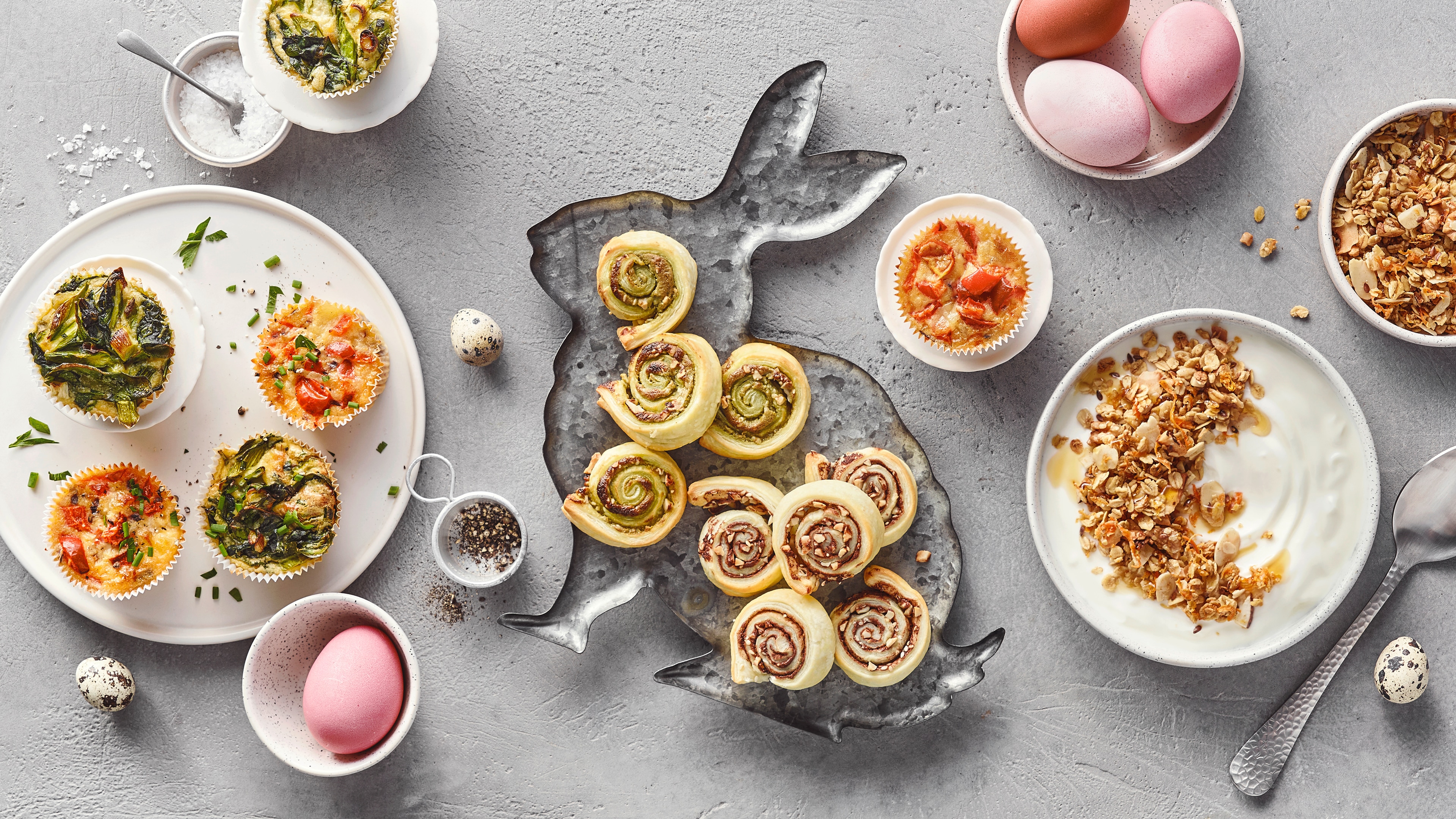 Muffins, Blätterteigschnecken und Granola auf österlich geschmücktem Tisch
