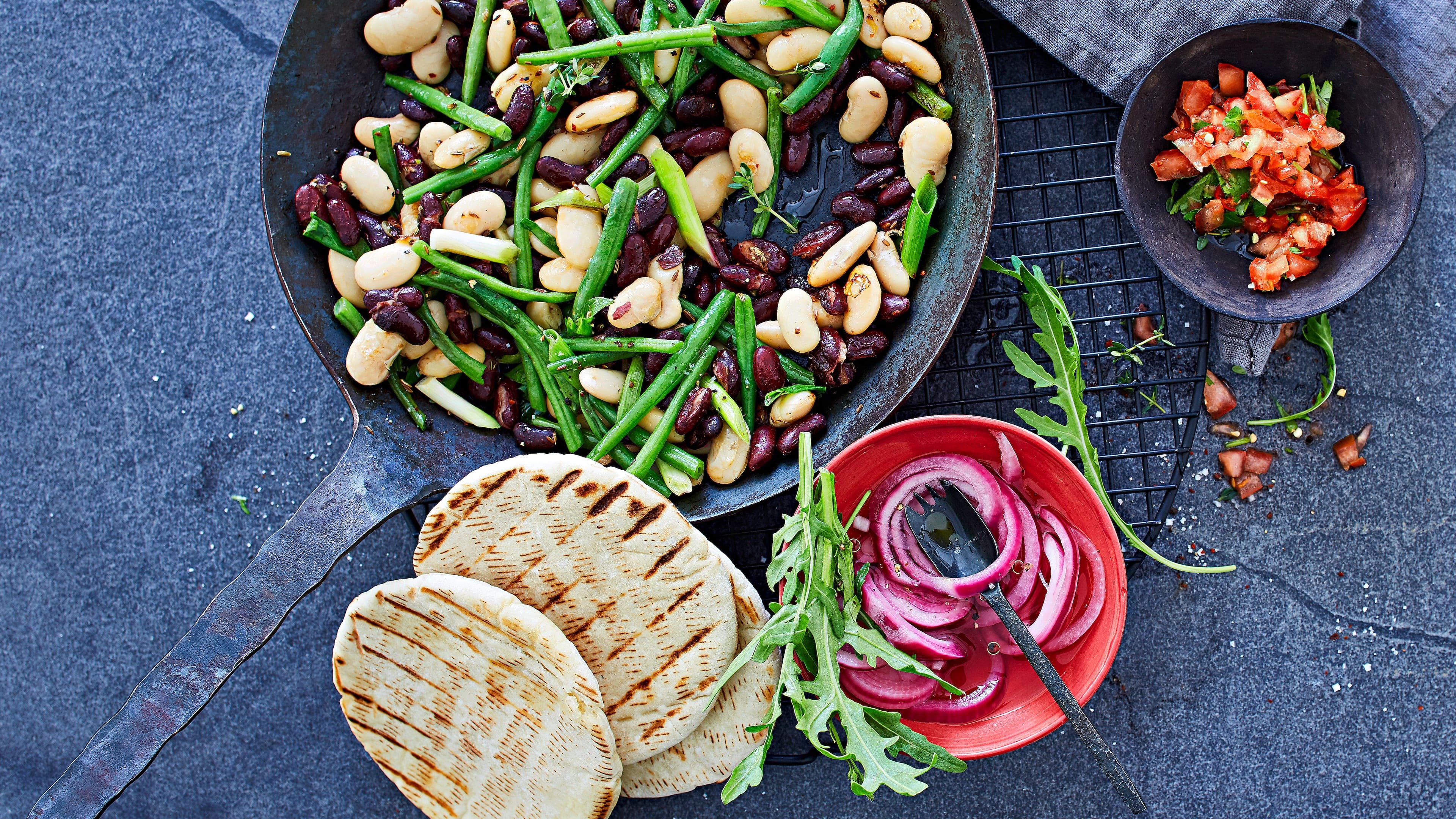 Bohnen-Pfanne mit Chili-Tomaten-Salsa In unserem Rezept für eine Bohnen-Pfanne mit Chili-Tomaten-Salsa kombinieren wir 3erlei Bohnen und servieren dazu eine selbstgemachte feurige Salsa und Pita-Brote.