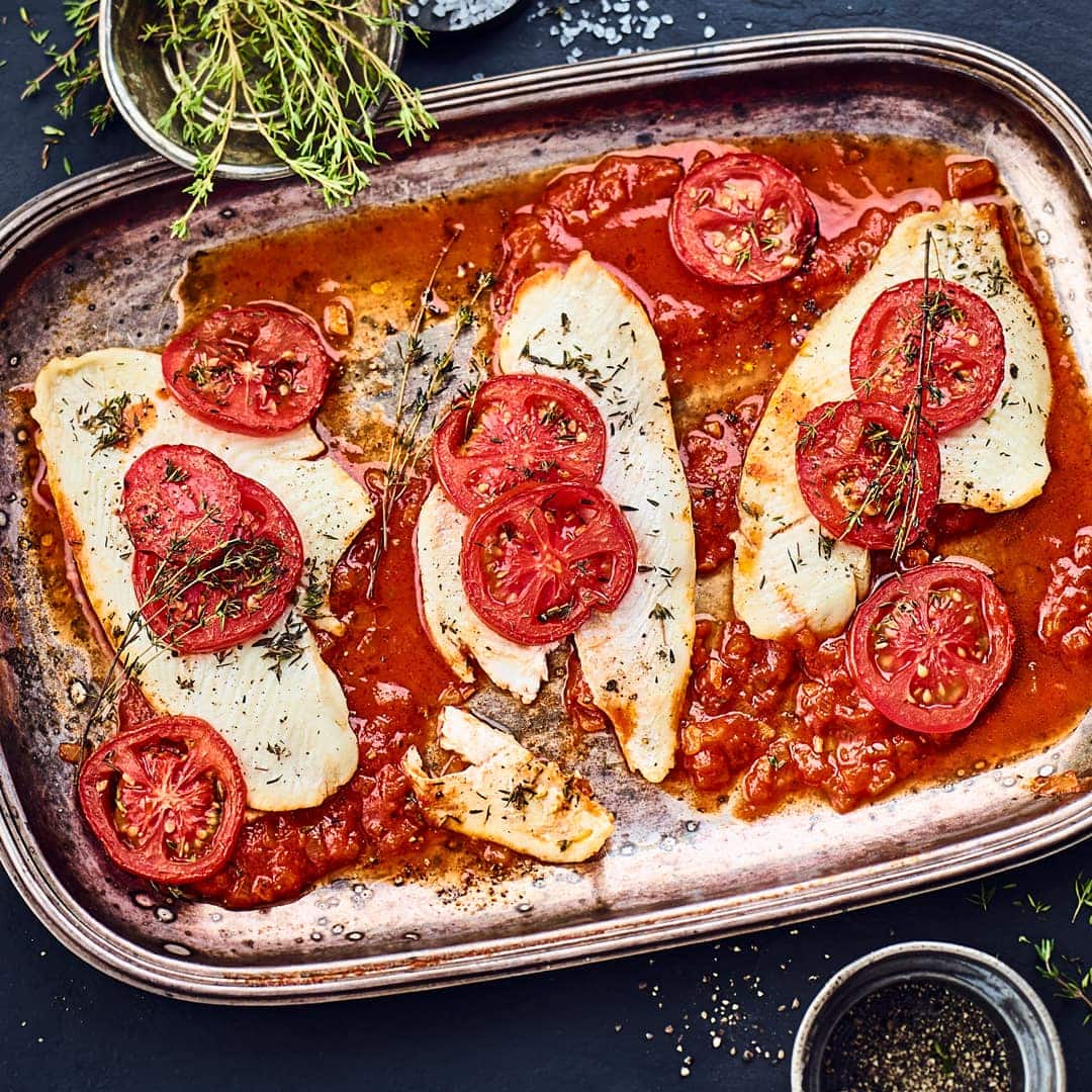 Für Fischliebhaber: Unser Rezept für Scholle im Ofen gebacken auf Tomaten-Knoblauch-Beet mit einem Schuss Weißwein und Thymian – probieren Sie es aus!