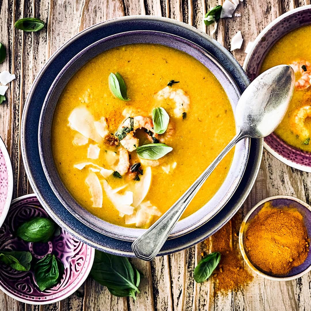 Raffinierte Vorspeise für Ihr Wintermenü oder einfach als warme Suppe an kalten Tagen: Probieren Sie unser Süppchen aus Kürbis, Kaki und Ingwer mit angebratenen Garnelen und Kokosraspeln!