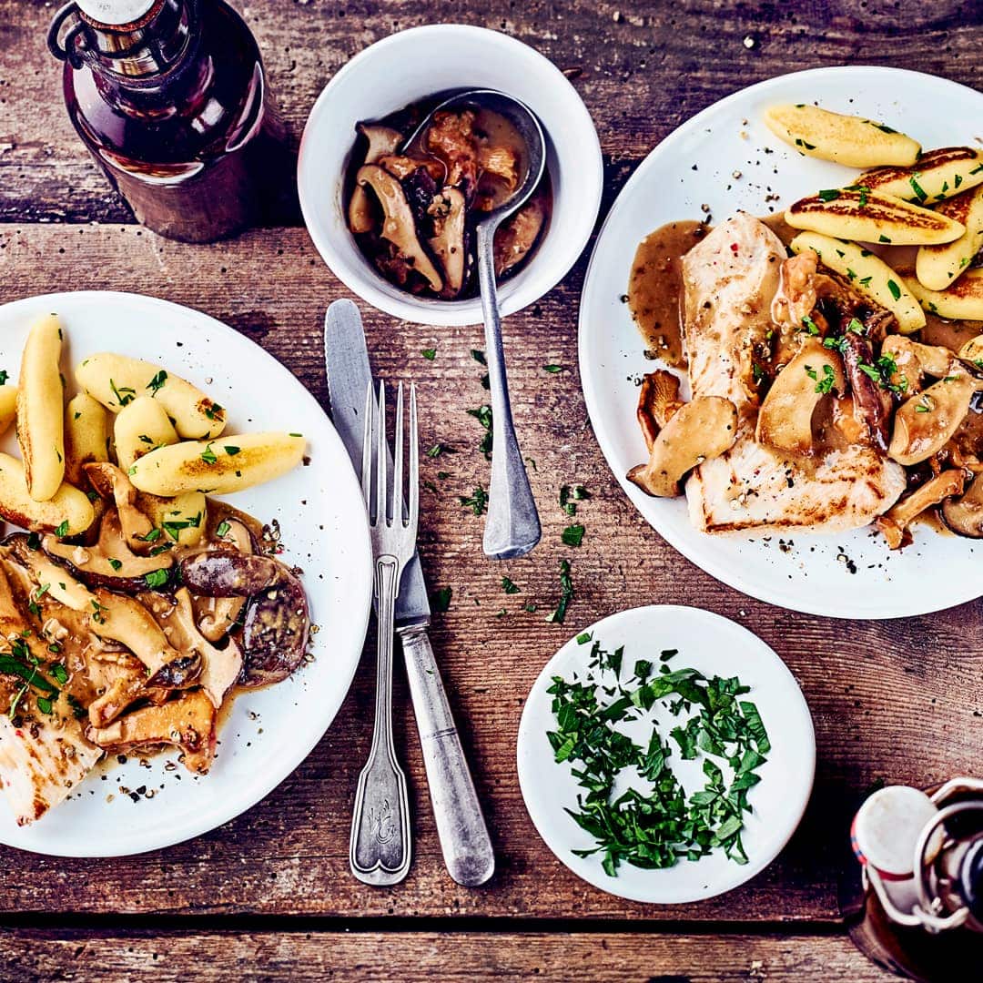 Saftige Putenschnitzel mit einer cremigen Pilzsauce und knusprigen Schupfnudeln mit Kräutern. Herzhafte Küche für Liebhaber deutscher Hausmannskost.
