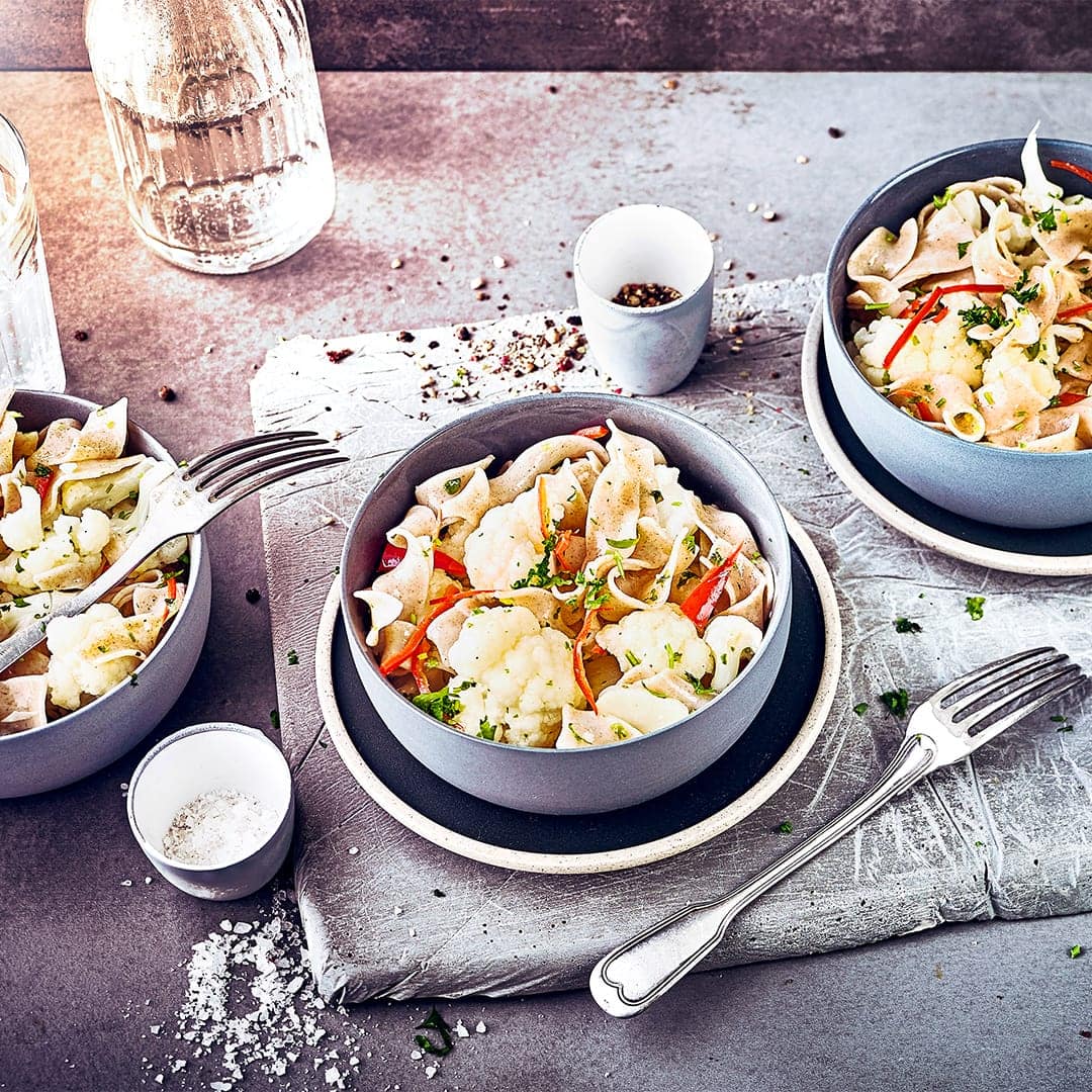 Fein geschnittener Knoblauch, Petersilie und gedünstete Zwiebeln verleihen unseren Vollkornnudeln mit Blumenkohl und Chili zusätzlich eine würzig Note.