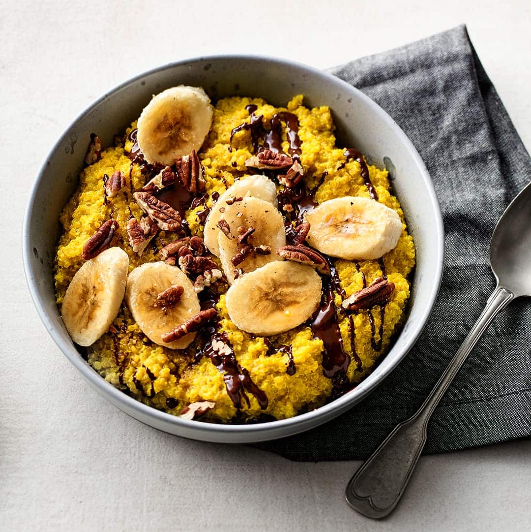 Köstlicher Quinoa-Porridge verfeinert mit Vanille und Kurkuma. Das Ganze wird mit Mandelmilch angerührt und mit feiner Zartbitterschokolade verfeinert.