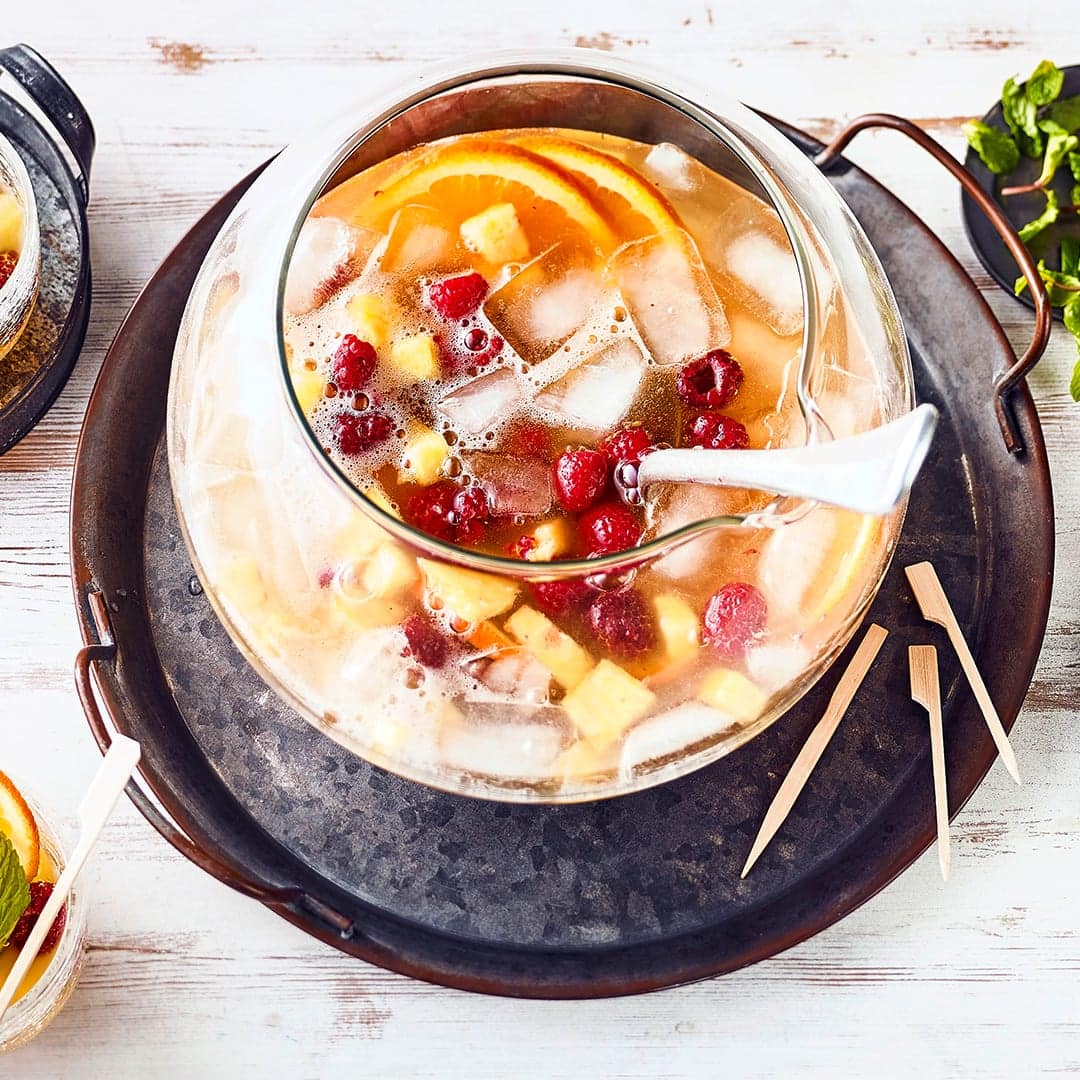 Für Ihre nächste Party im Sommer: Fruchtige Sommerbowle mit Himbeeren, Ananas, Fruchtnektar, Sekt und Weißwein. Am besten eiskalt genießen!