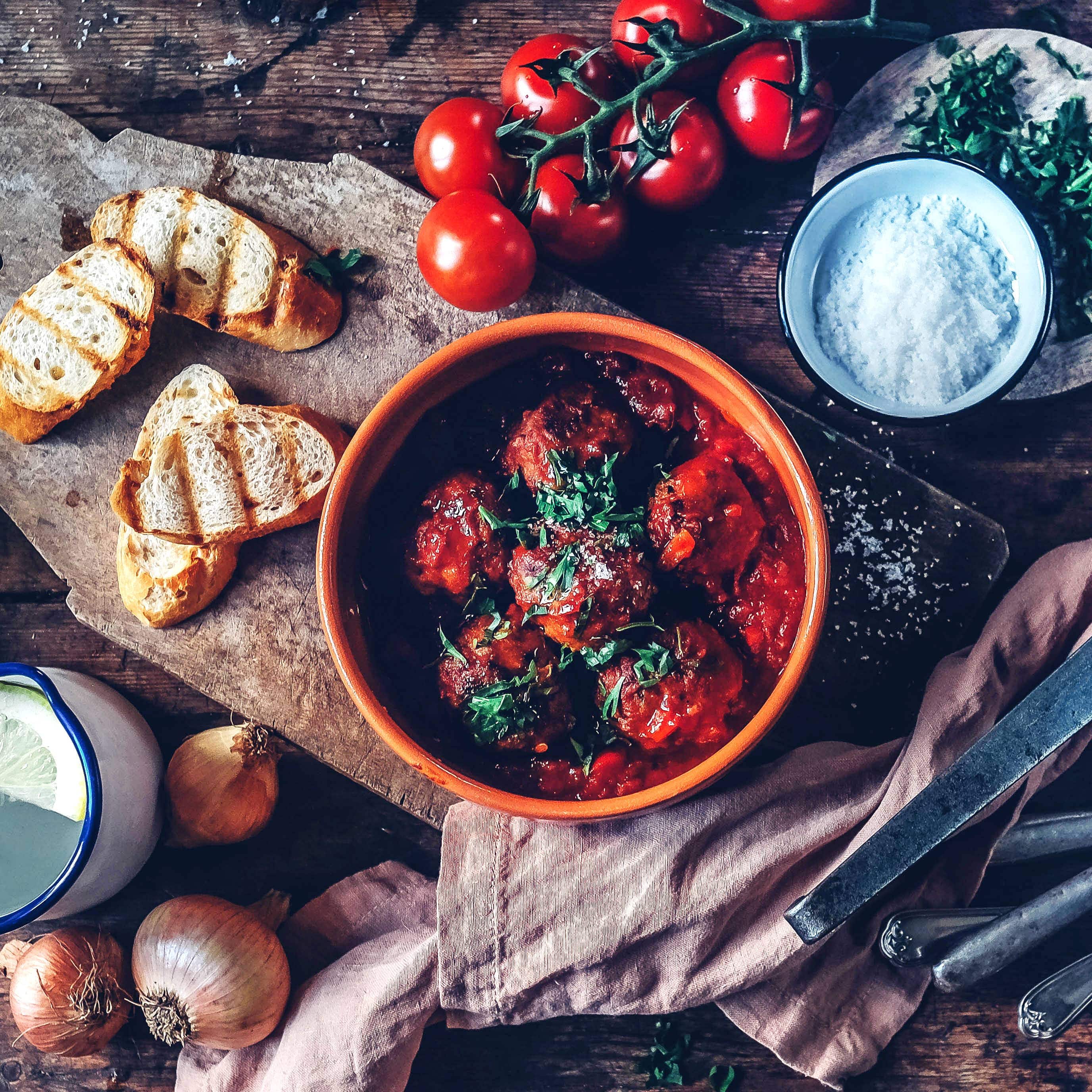 Spanische Tapas für zuhause: Lecker würzige Albondigas in köstlicher Tomatensoße – dazu passt Baguette.