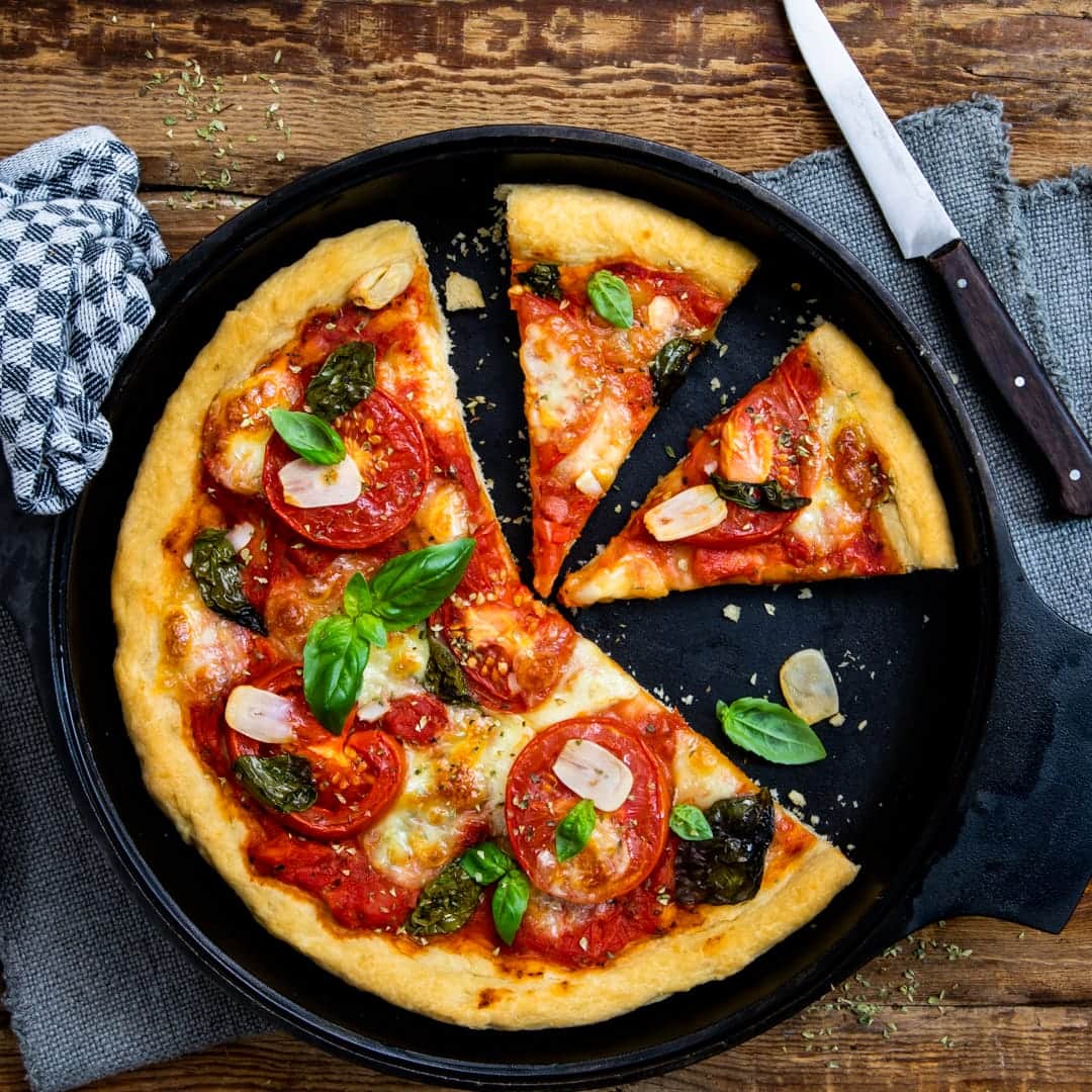 Der fluffige Teig macht diese American Pizza mit Mozzarella, Basilikum, Tomaten und Knoblauch doppelt lecker – zum reinbeißen!