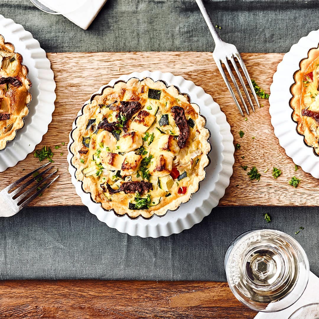 Mediterraner Snack für zuhause: Kleine selbstgemachte Mürbeteig-Törtchen mit allerlei mediterranem Gemüse und Feta.