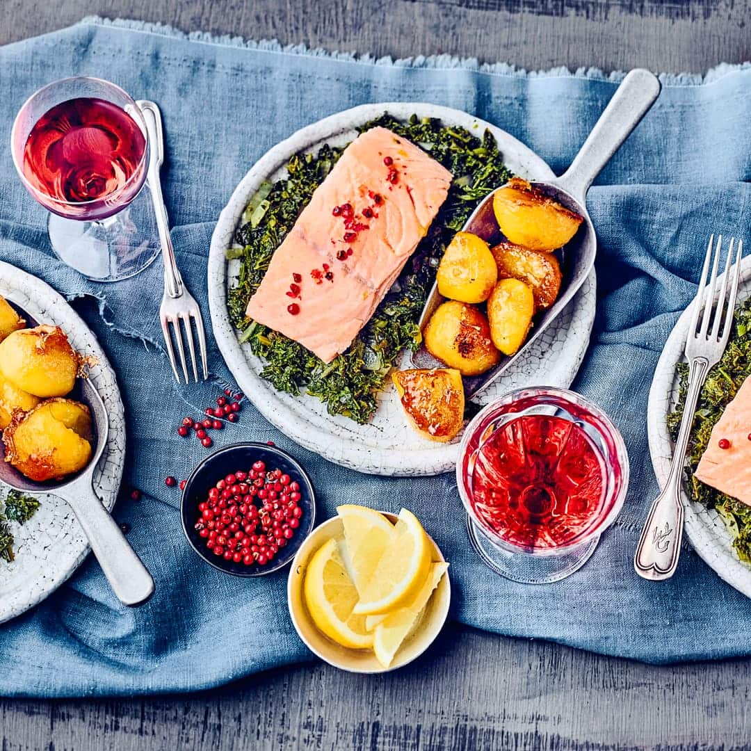 Probieren Sie einmal unsere Variante dieses Traditionsgerichts aus dem Norden Deutschlands: Gedünstete Tranchen von Lachs auf Grünkohl-Gemüse mit karamellisierten Kartoffeln – deftig und lecker!