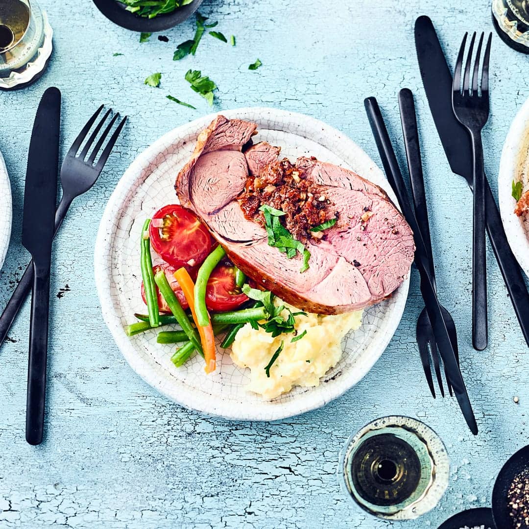 Probieren Sie unsere pikant gefüllte Lammkeule mit einer Gemüsebeilage aus grünen Bohnen, Cocktailtomaten und Paprika – gewürzt wird der Braten mit Harissa.