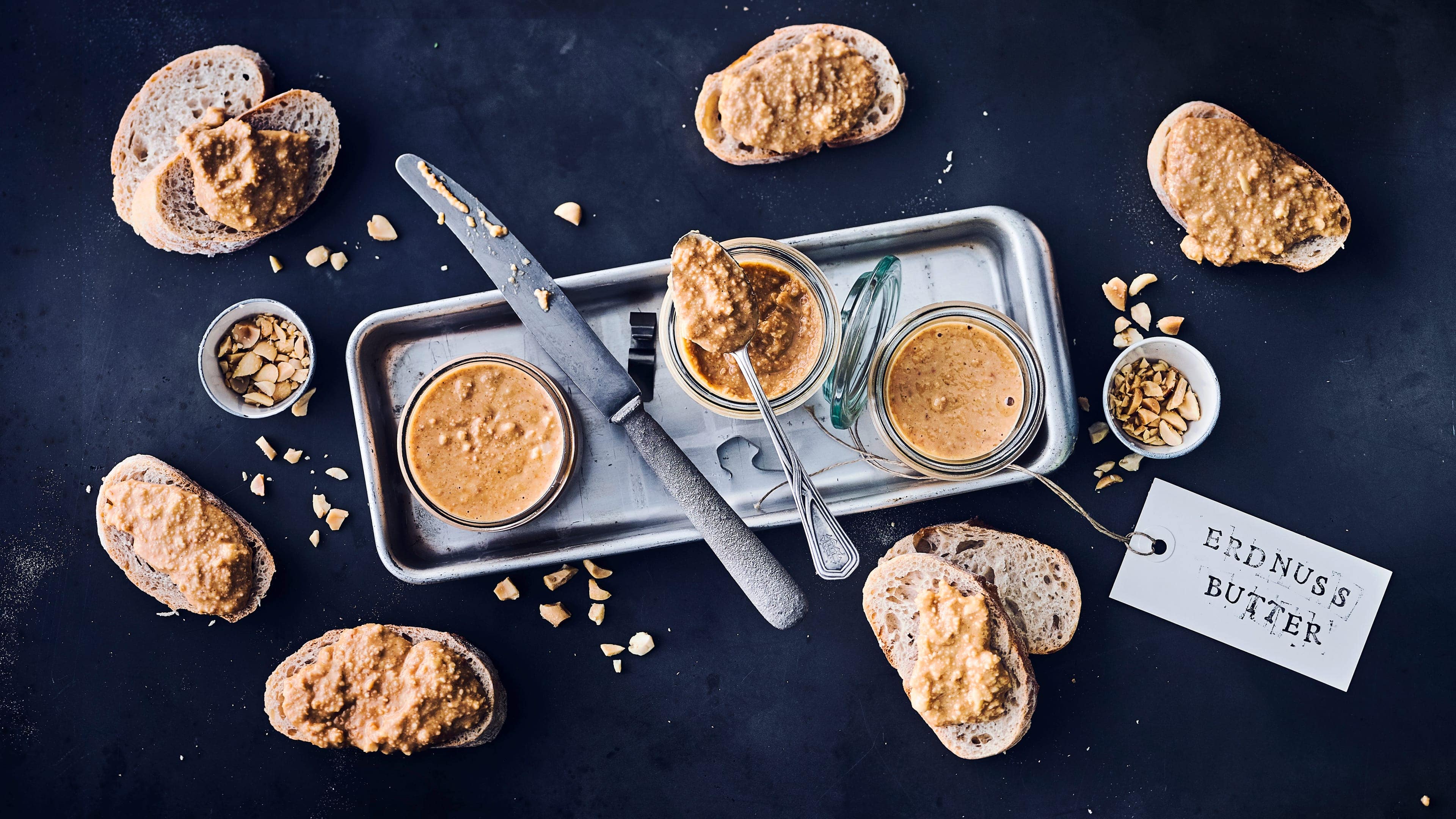 Erdnussbutter Selbst gemachte Erdnussbutter mit gerösteten Erdnüssen zum Frühstück auf einem knackigen Baguette – wer kann da schon wiederstehen?!