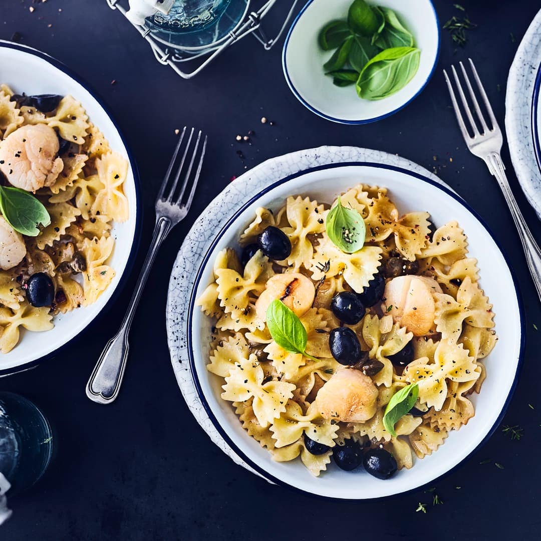Sommerliches Pastagericht mit Jakobsmuscheln gesucht? Gefunden – wir vereinen Farfalle mit Jakobsmuscheln, Oliven und Kapern.