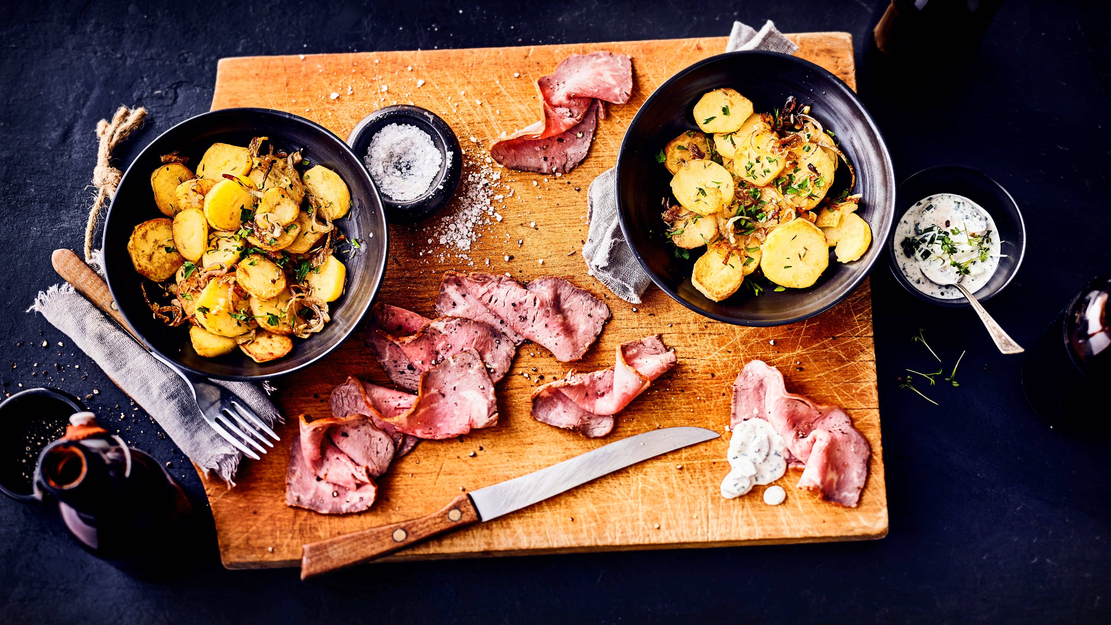Roastbeef mit Bratkartoffeln Ein klassischer Mittagstisch: Gebratenes Roastbeef in dünne Scheiben geschnitten, mit Bratkartoffeln, einer würzigen Zwiebel-Pilz-Pfanne und selbstgemachter Remoulade serviert.