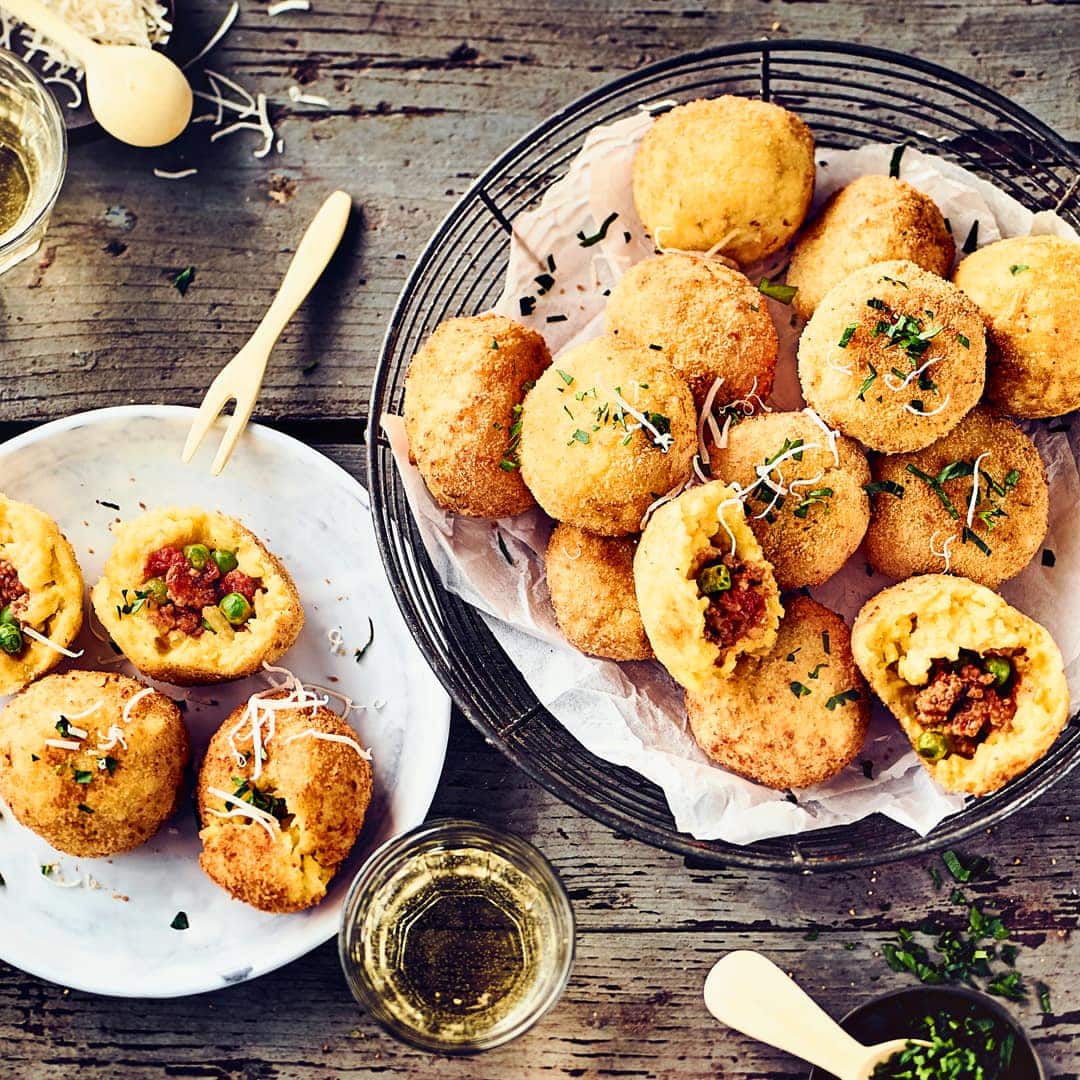 Arancini Bällchen sind köstliche kleine frittierte Reis-Bällchen, gefüllt mit Hackfleisch, Speck und Erbsen.
