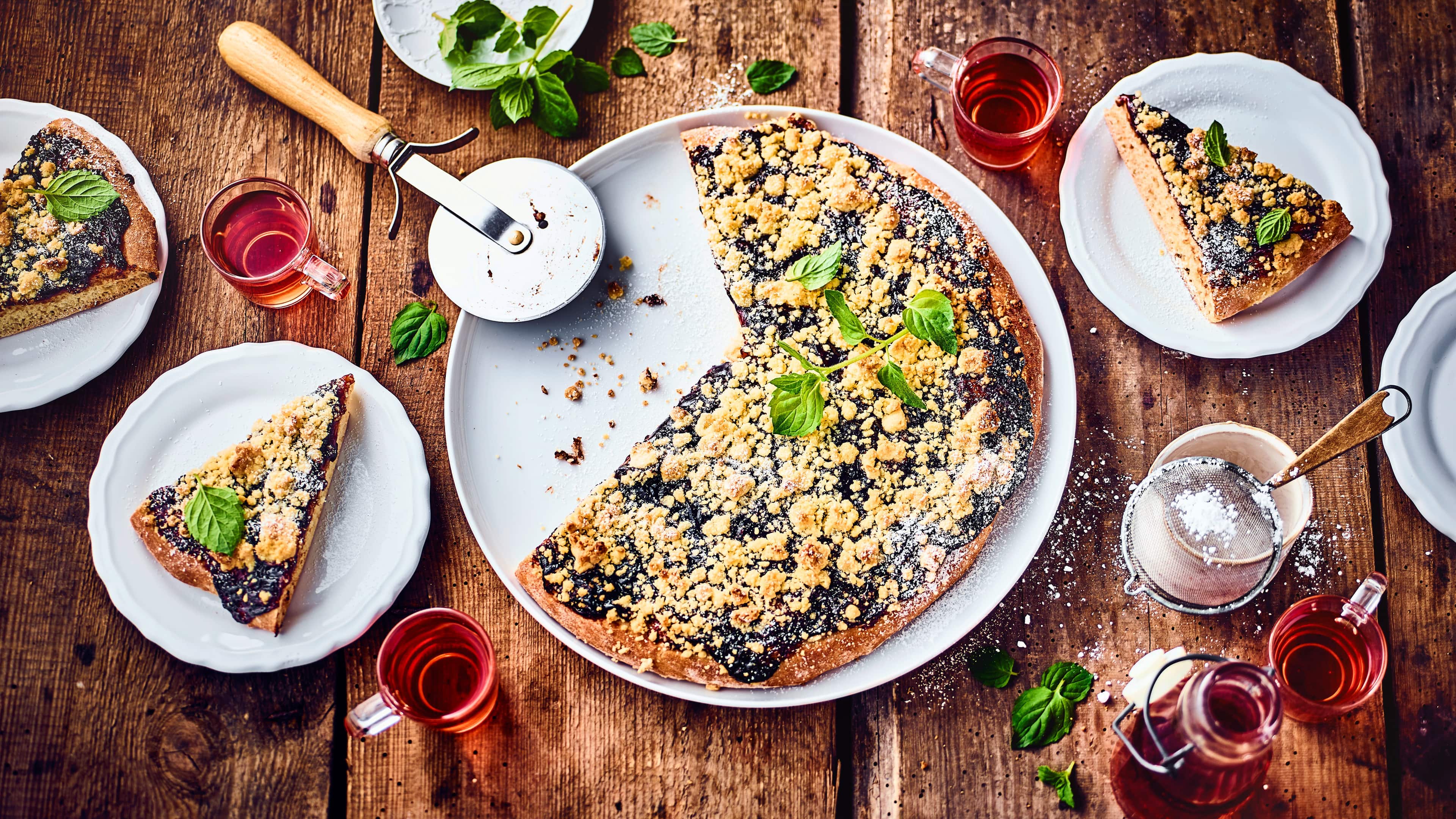 Süße Pflaumen-Pizza Unser Rezept für süße Pizza interpretiert den Klassiker der italienischen Küche auf unerwartete Weise und kombiniert ihn mit saftigen Pflaumen und zarten Streuseln.