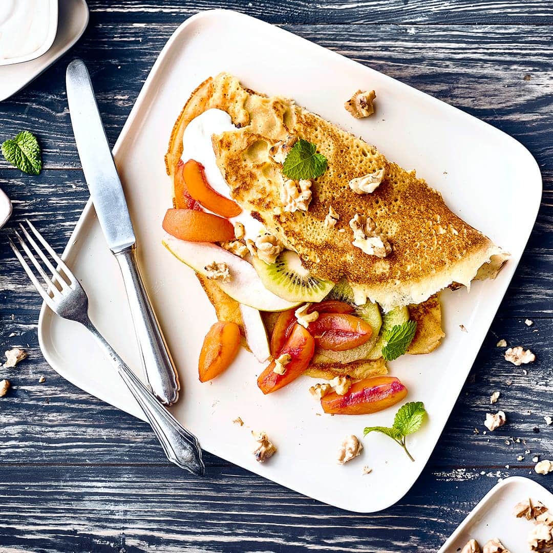 Ein Dessert ohne Gluten und Laktose: Backen Sie unsere Hirse-Mais-Pfannkuchen mit einer Füllung aus Obst und Quarkcreme und gerösteten Walnüssen!