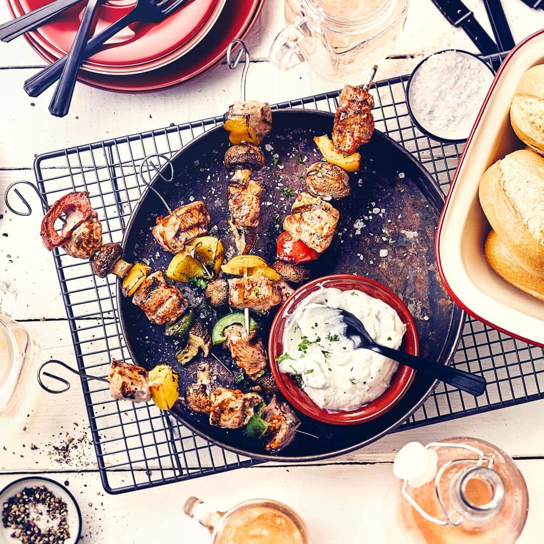 Mediterraner Genuss für Ihre nächste Grillparty: Pikant gewürzte Fleischspieße, dazu Zaziki und Baguette Brötchen.