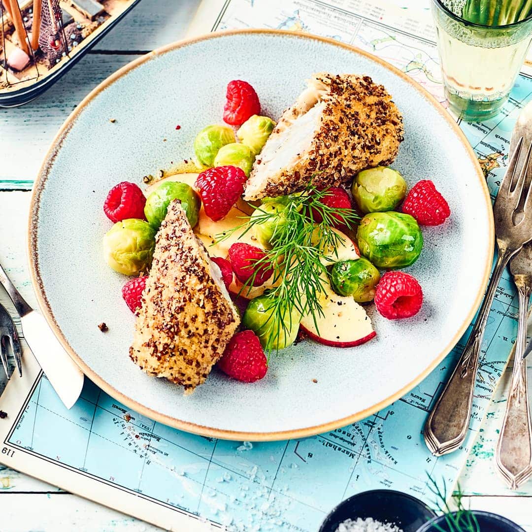 Knusprige Schwarzbrotkruste, saftiges Fischfilet: Probieren Sie unser Rezept für paniertes Seelachsfilet aus! Dazu gibt's Rosenkohlsalat mit Äpfeln und feinem Ingwer-Dressing.