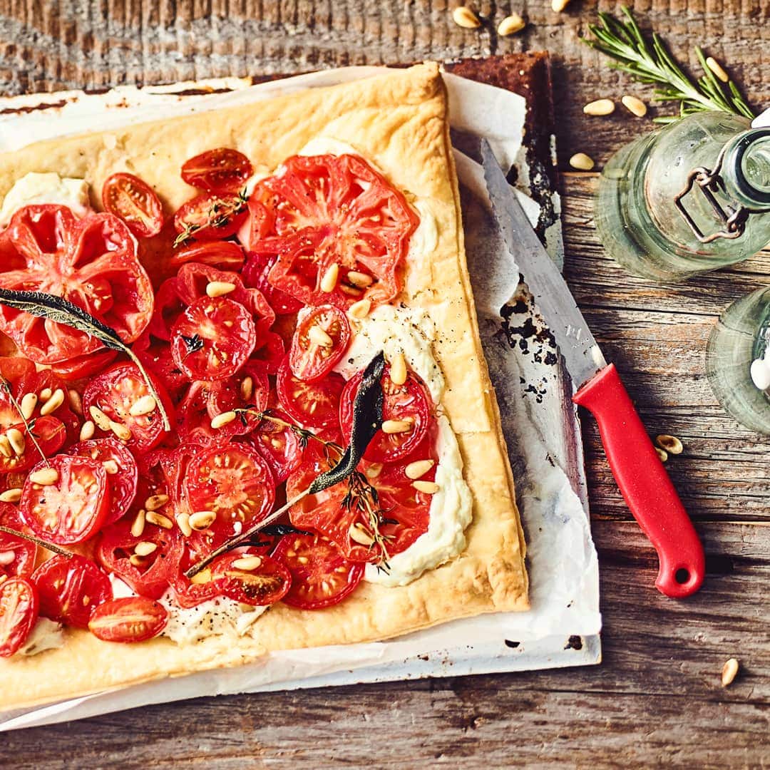 Leichtes Sommergericht vom Blech: Probieren Sie unsere Tomaten-Pinien-Tarte mit Ricotta und Zitronenthymian – vegetarisch und mediterran!