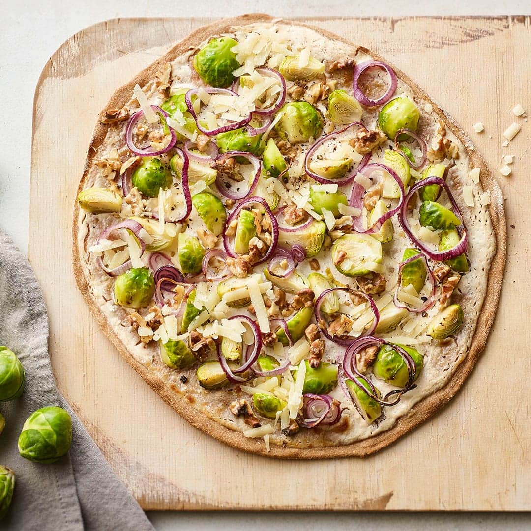 Kochen Sie unser Rezept für Flammkuchen mit Rosenkohl in 40 Minuten nach & servieren Sie Ihren Gästen feines Gemüse mit Walnüssen auf knusprigem Dinkelteig.