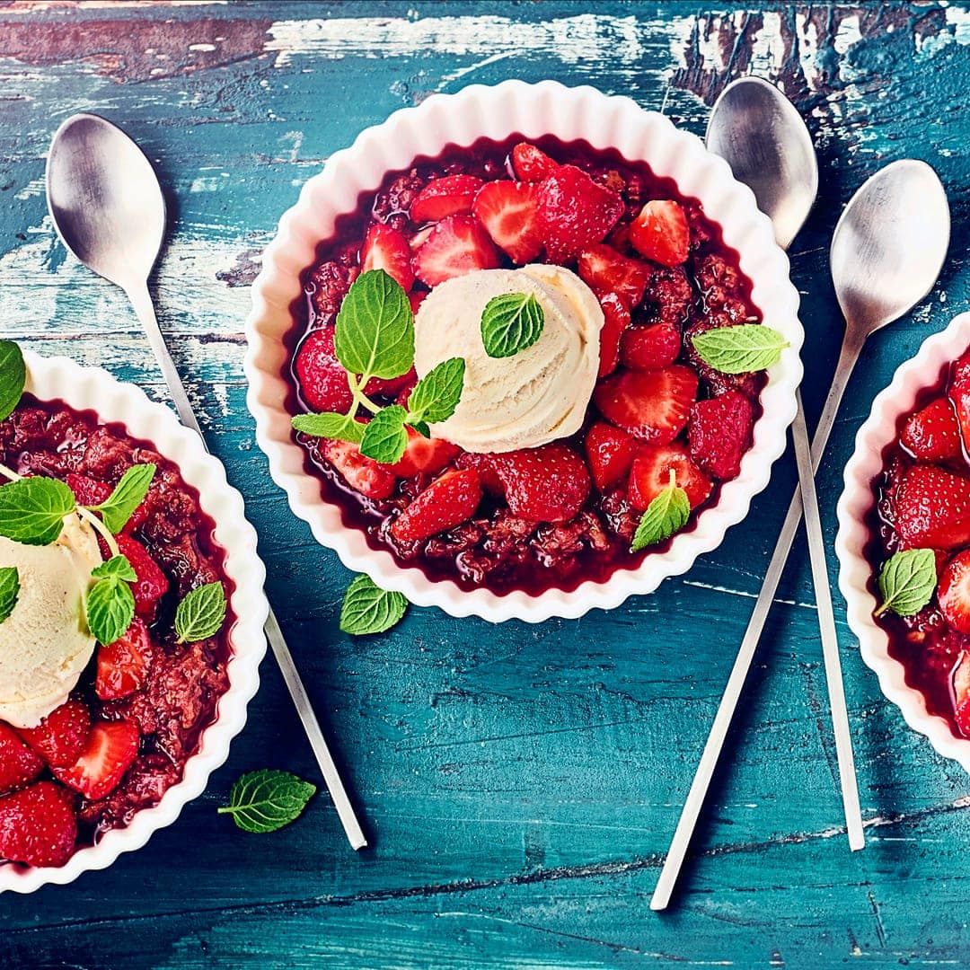 Fruchtiger Nachtisch: Genießen Sie frische Erdbeeren in einer Marinade aus Honig und Zitronenschale auf einer Rhabarber-Dattel-Creme mit Vanille-Eis!