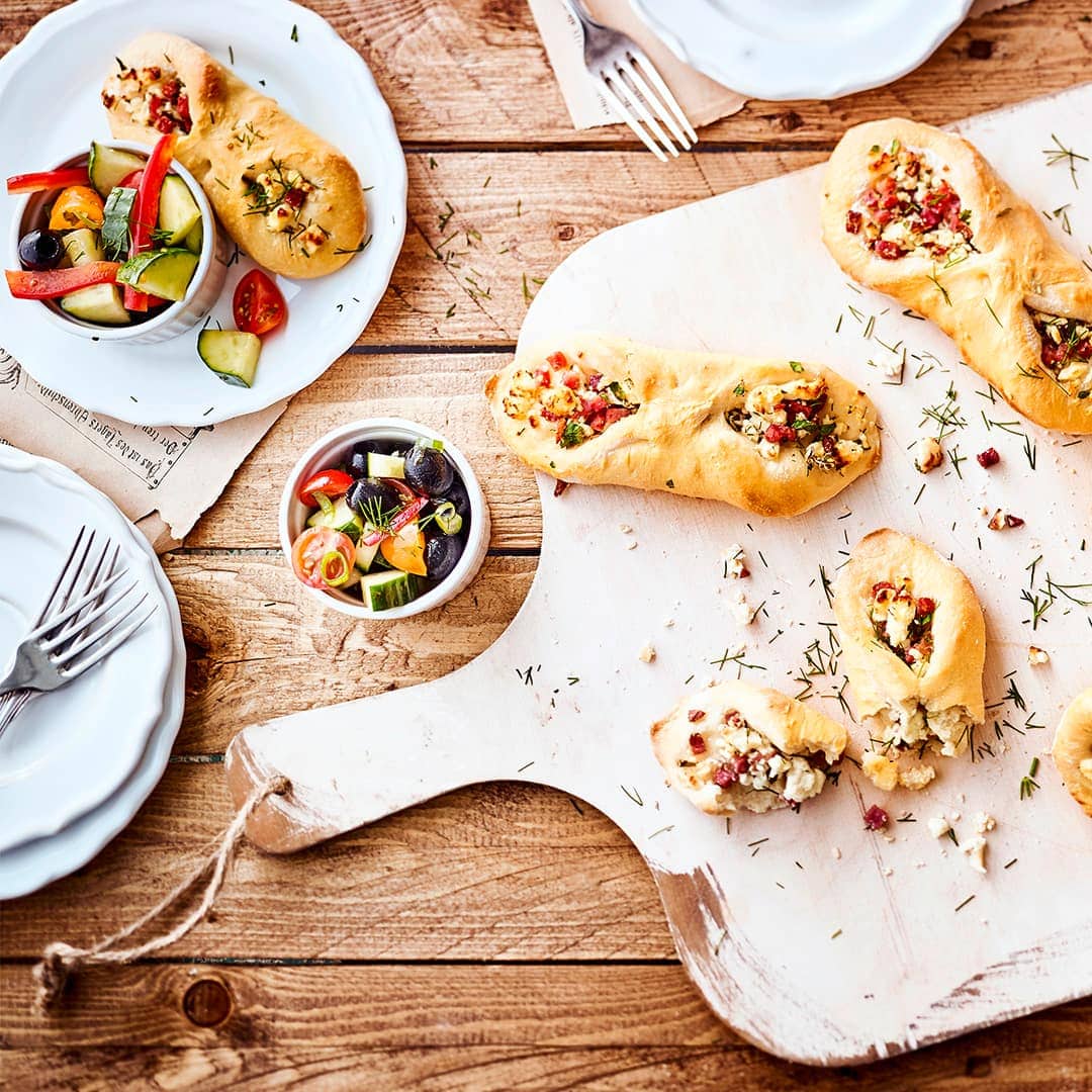 Unser Tipp für eine mediterrane Zwischenmahlzeit: Probieren Sie unseren Snack aus selbstgemachtem Fladenbrot mit Feta-Käse und Schinken, dazu einen bunten Gurke-Tomate-Paprika-Salat mit Oliven!